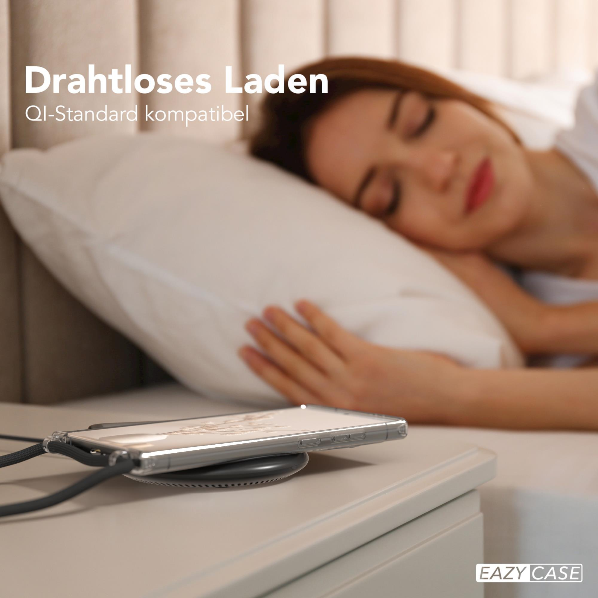 Ein Telefon auf einem kabellosen Ladegerät, mit einer schlafenden Frau im verschwommenen Hintergrund.