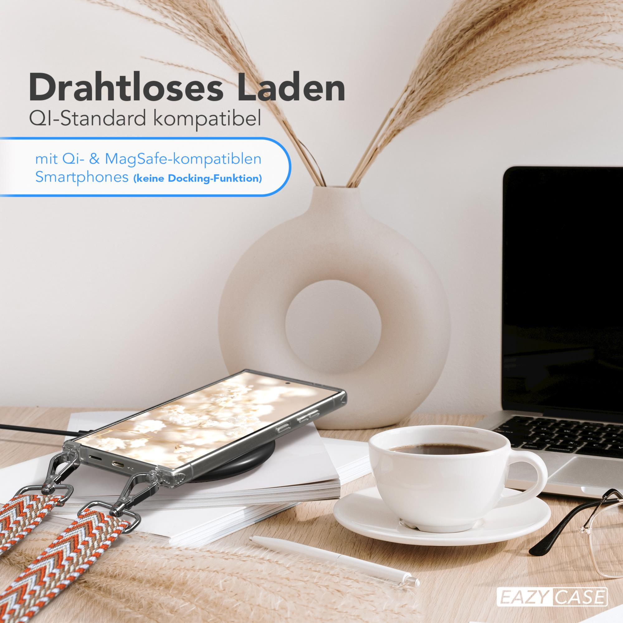 Ein Telefon lädt auf einem kabellosen Ladegerät in der Nähe einer Vase und einer Tasse Kaffee.
