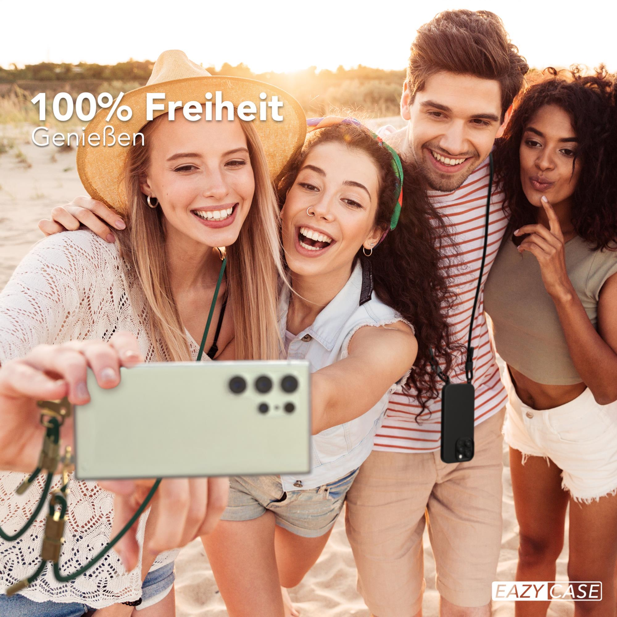 Vier Freunde machen ein Selfie. Einer hält das Telefon mit einem Halsband, Strandhintergrund.