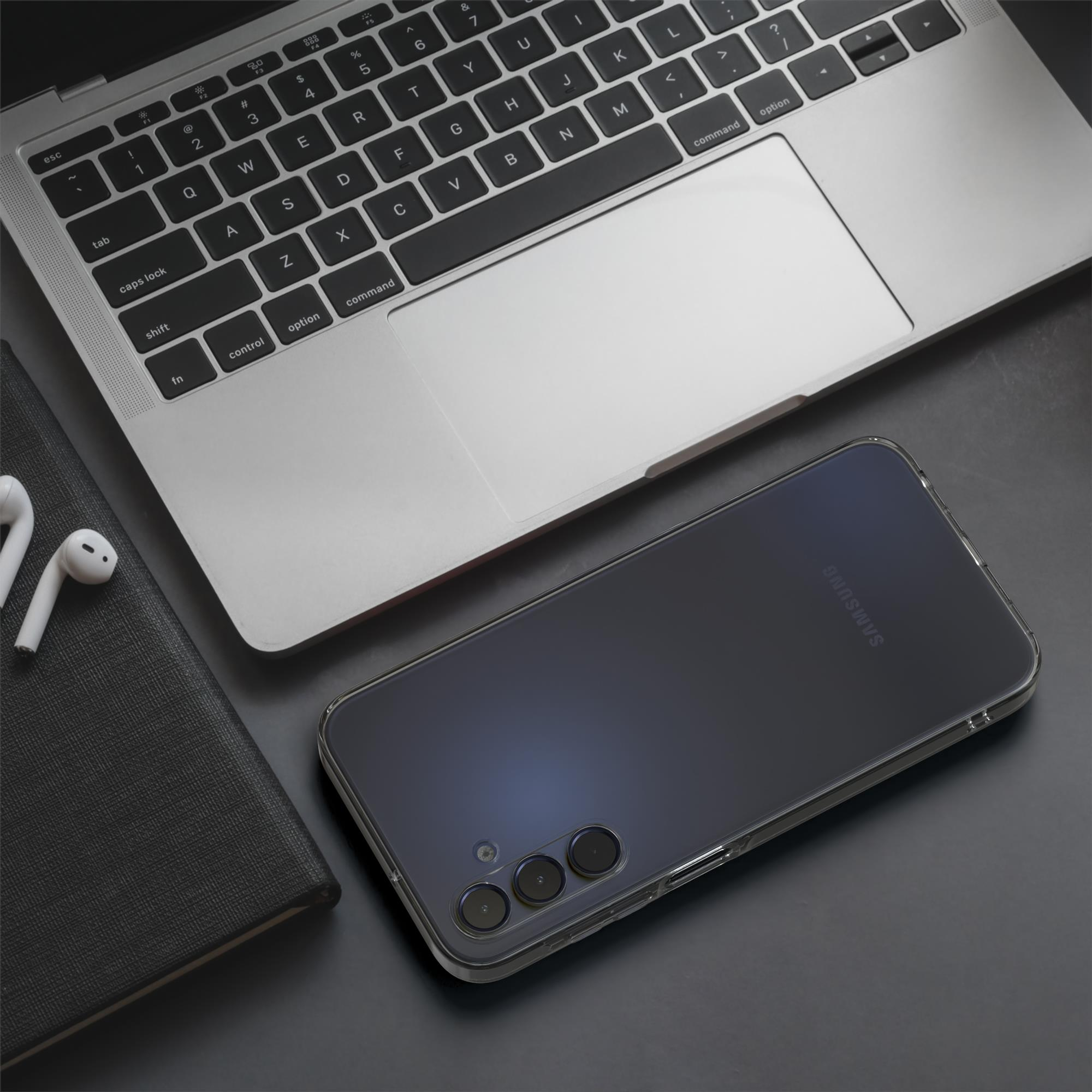 Laptop, Telefon, Kopfhörer und Notizbuch auf einem schwarzen Schreibtisch. Telefon ist klar, mit Samsung Logo.
