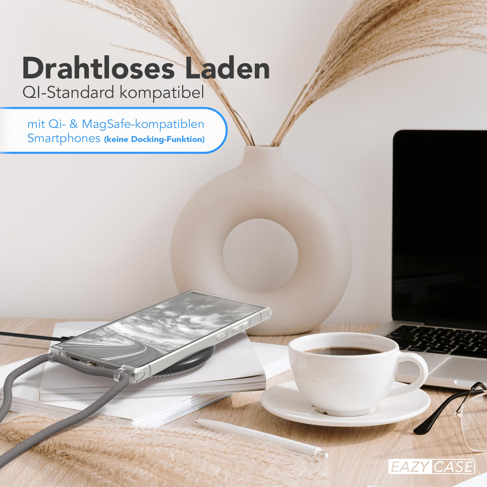 Telefon auf kabellosem Ladegerät, Vase mit Pampasgras, Kaffeetasse, Brille.