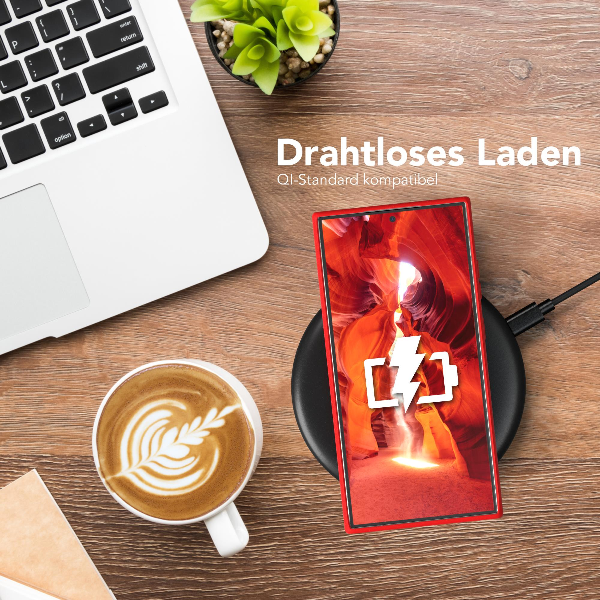 Ein Telefon wird drahtlos geladen. Auf einem Holztisch befinden sich eine Kaffeetasse und ein Laptop.
