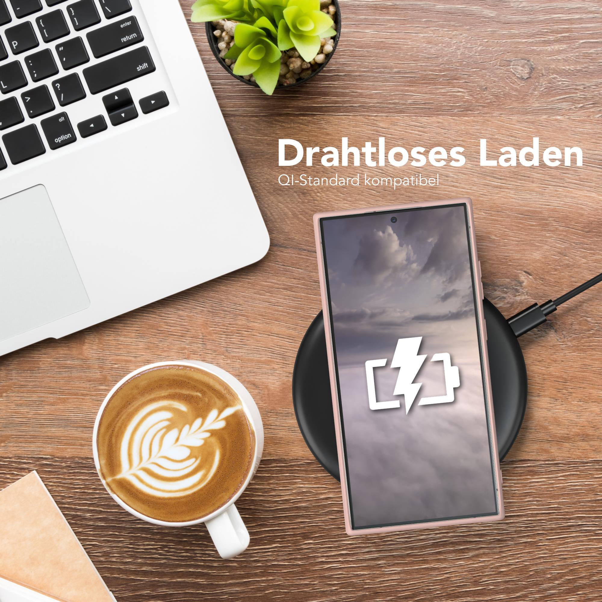Telefon auf kabellosem Ladegerät, Laptop, Kaffee und Pflanze auf Holzschreibtisch.