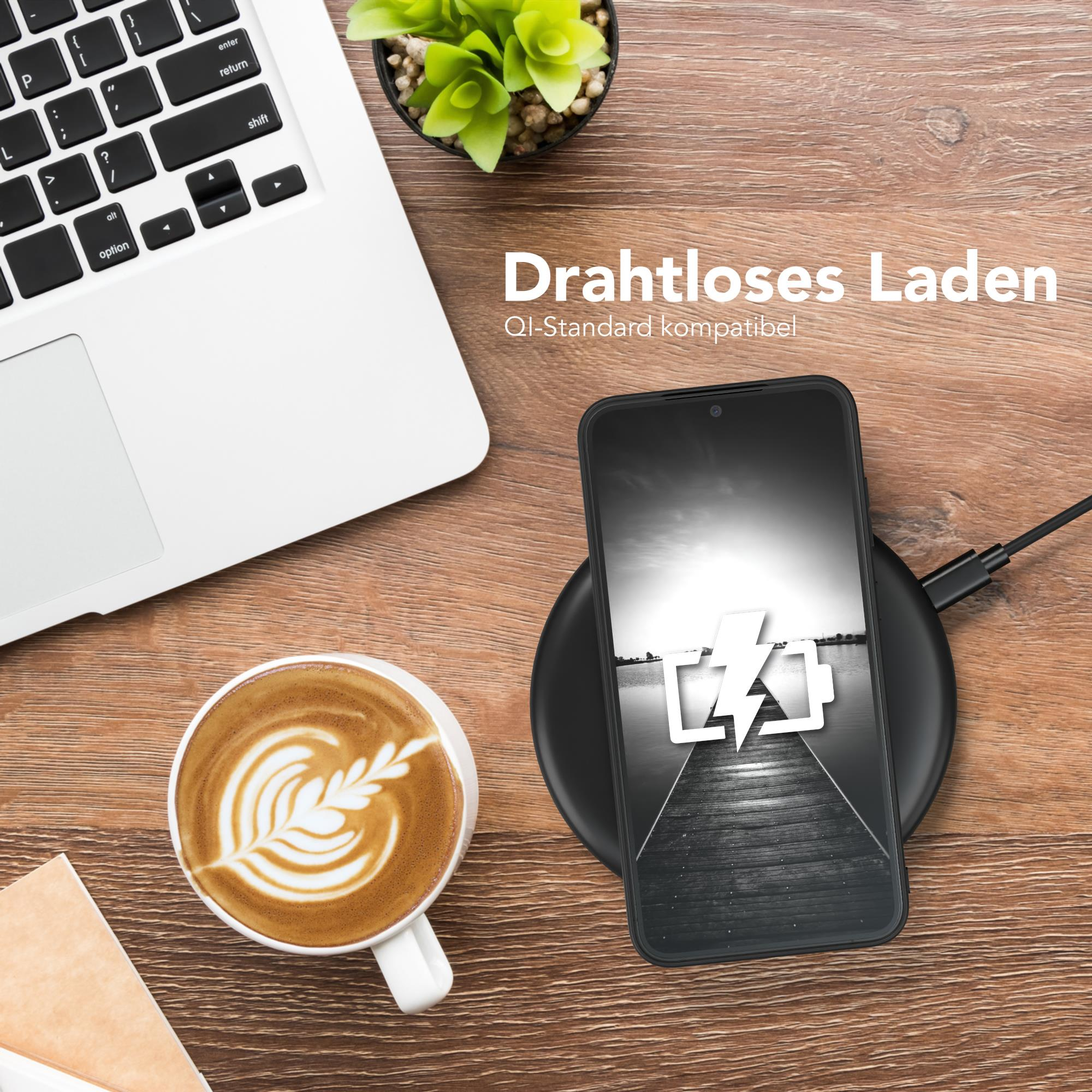 Ein Laptop, eine Kaffeetasse und ein Telefon auf einem Holztisch. Das Telefon wird kabellos geladen.