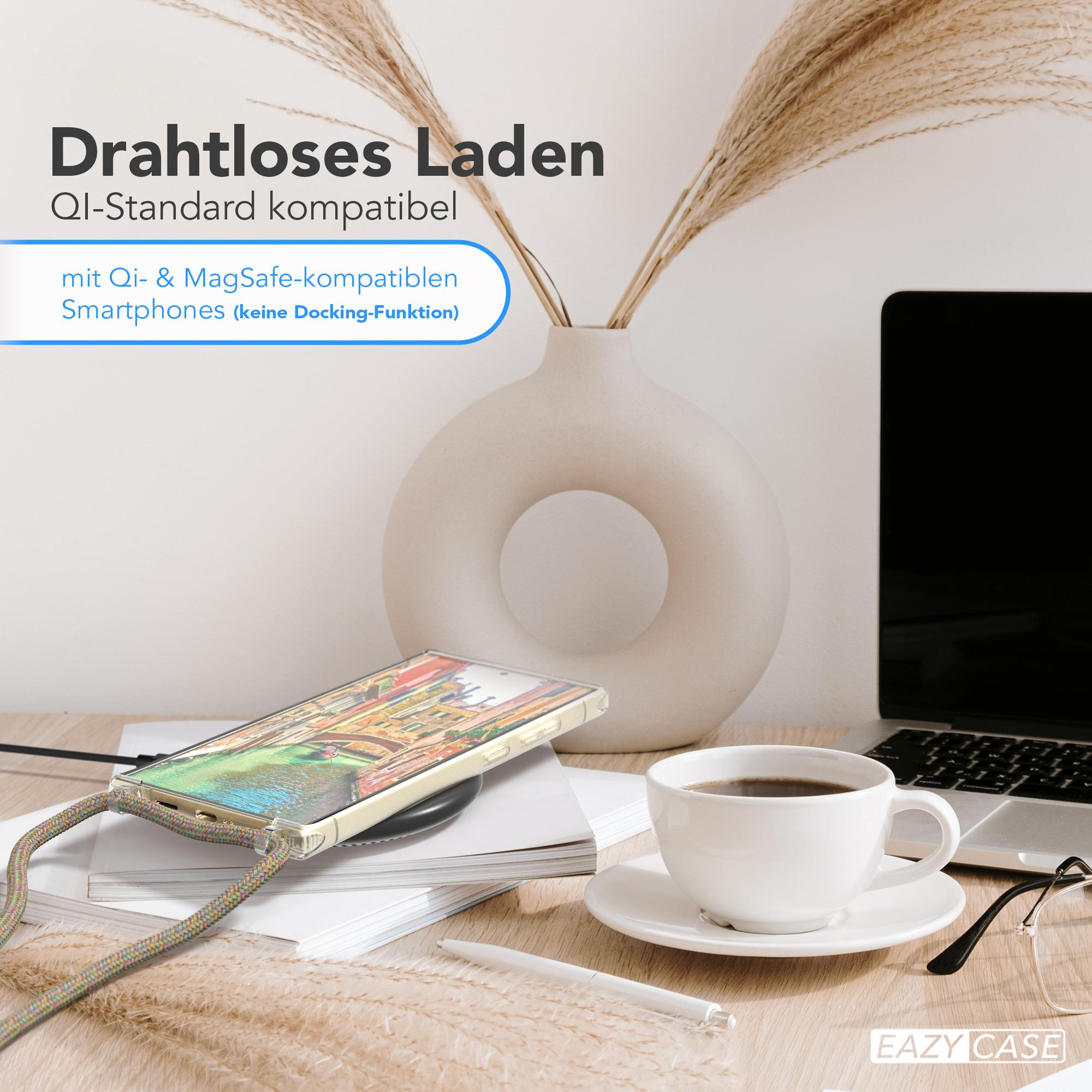 Telefon auf kabellosem Ladegerät, Laptop, Kaffee und Vase mit Schilf auf Holztisch.