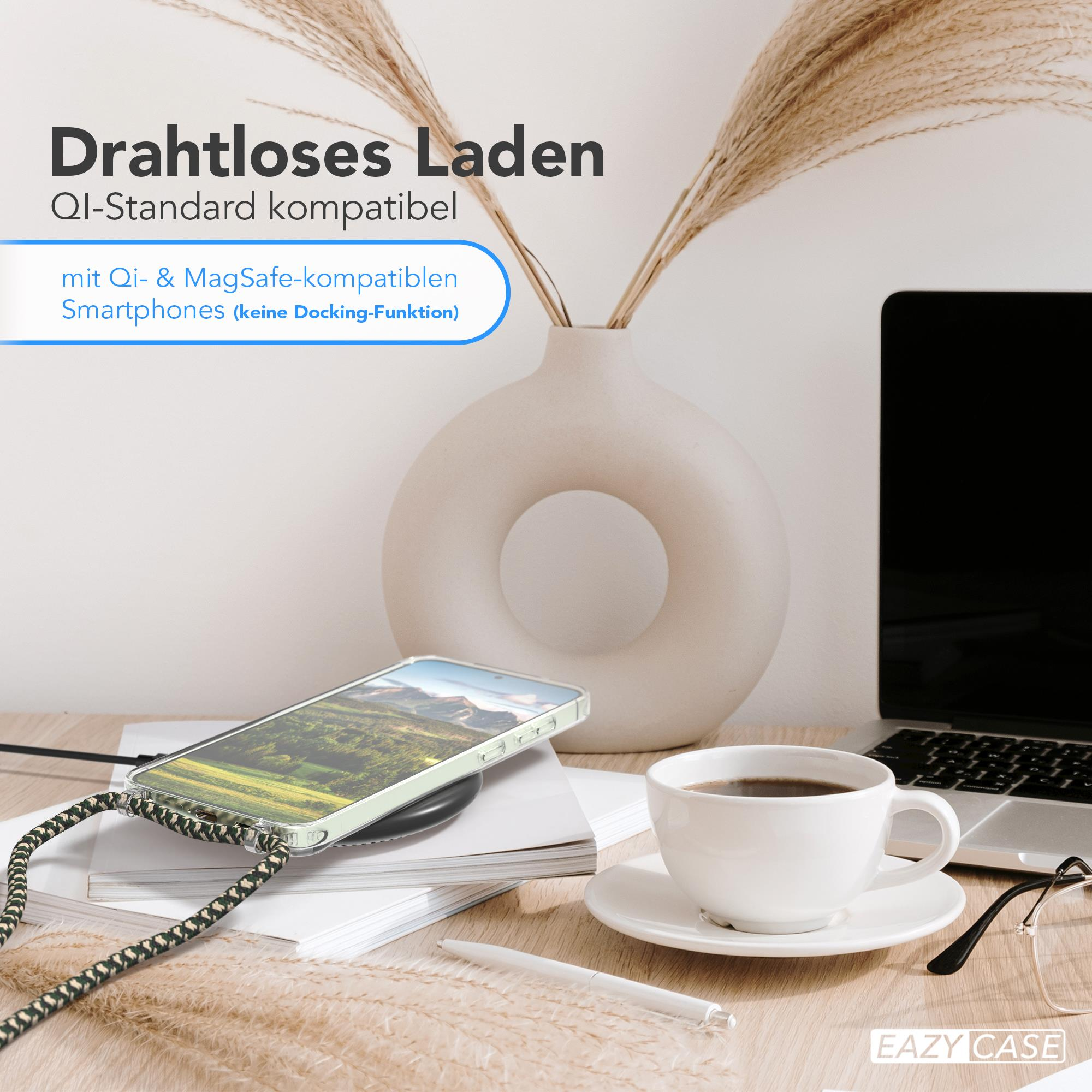 Ein Telefon liegt auf einem kabellosen Ladegerät. Eine Kaffeetasse, ein Stift und ein Laptop stehen auf dem Tisch.