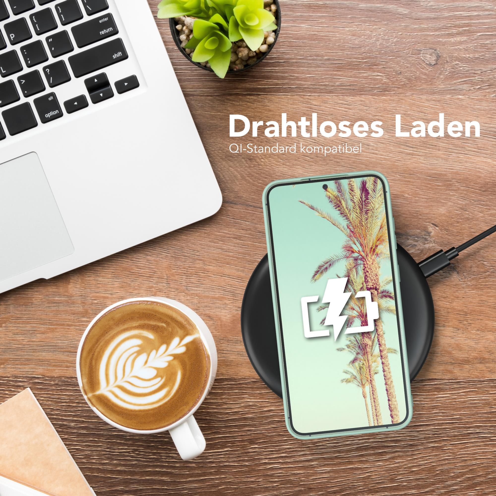 Telefon drahtlos auf einem Pad laden, neben Laptop und Kaffee.