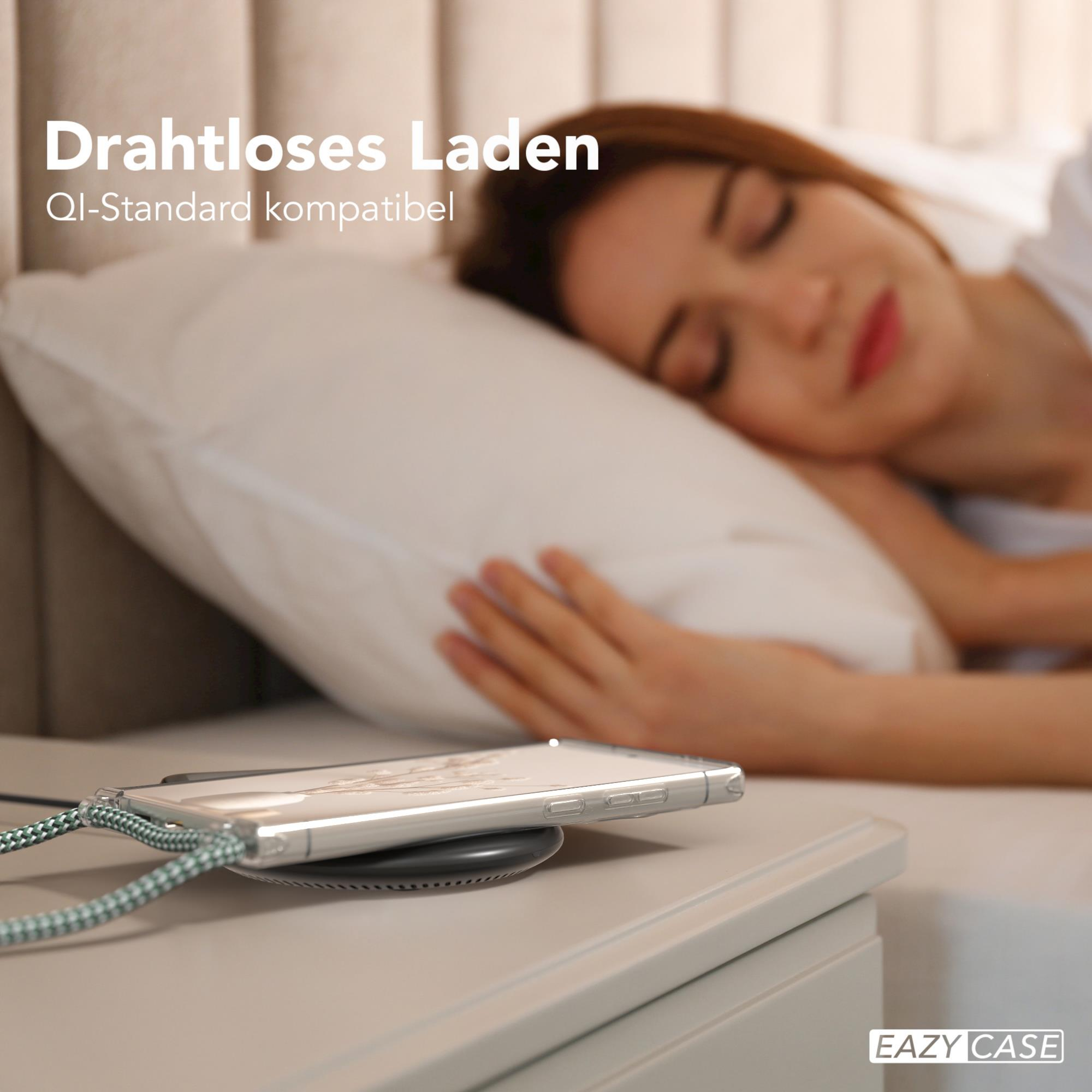 Ein Telefon wird kabellos auf einem Nachttisch aufgeladen. Im Hintergrund schläft eine Frau.