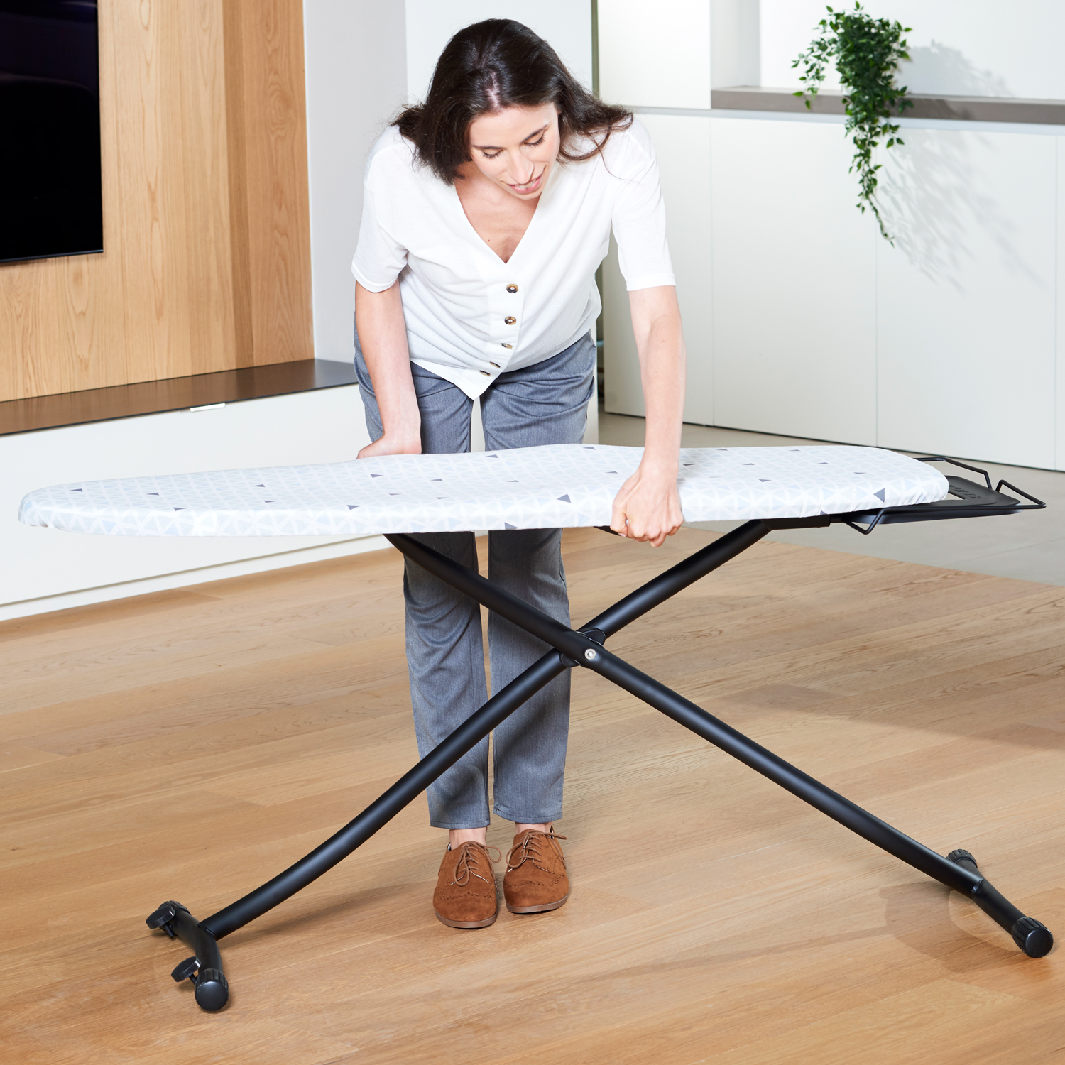 Una mujer planchando ropa en una tabla de planchar.