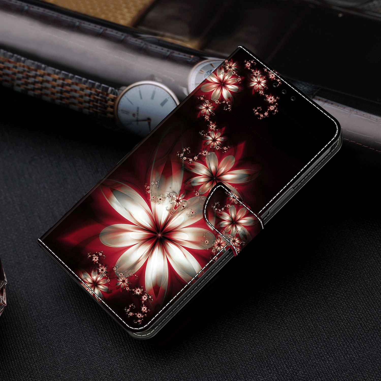 Una funda de teléfono con un diseño floral. La funda está cerrada, con un patrón floral rojo. El fondo es negro.