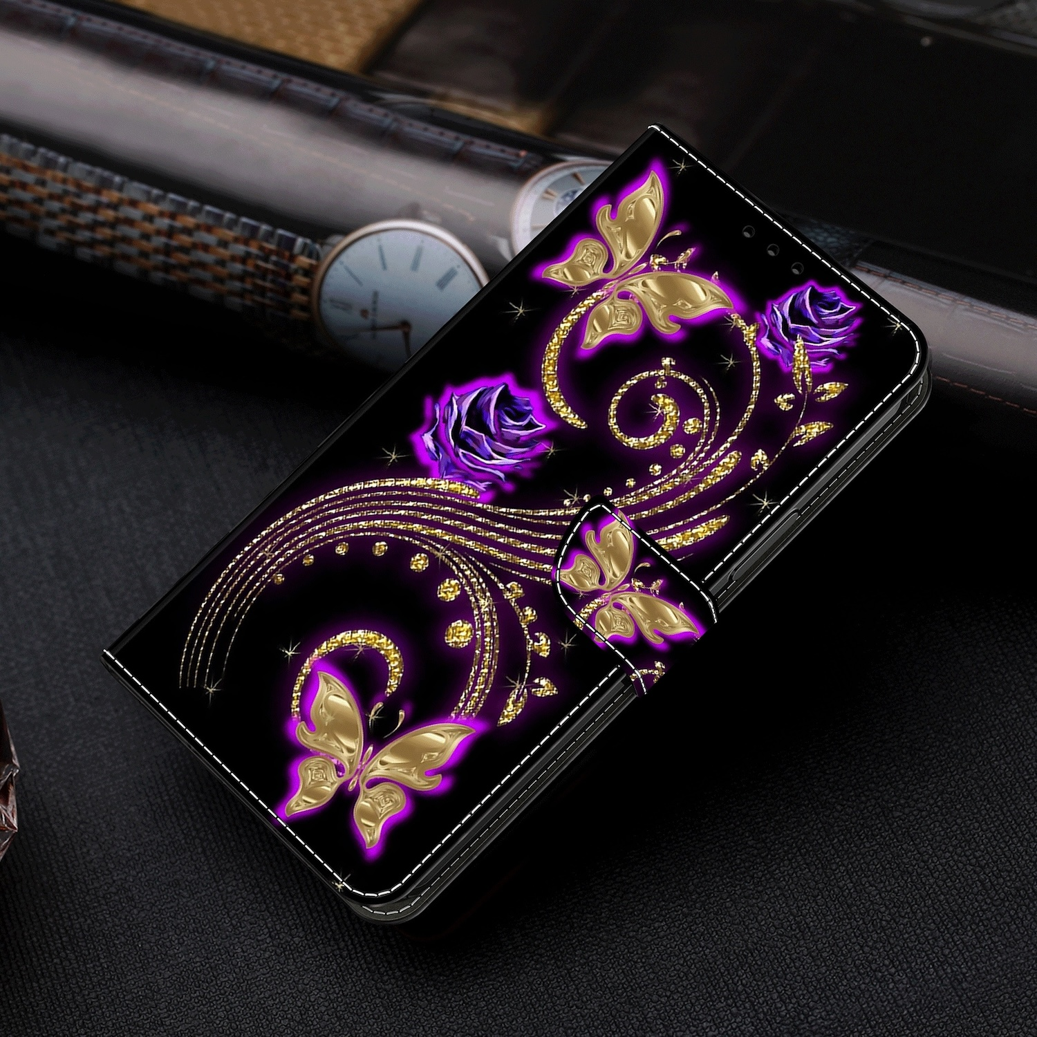 Funda de teléfono negra con diseño de mariposas doradas y rosas moradas sobre una superficie oscura.