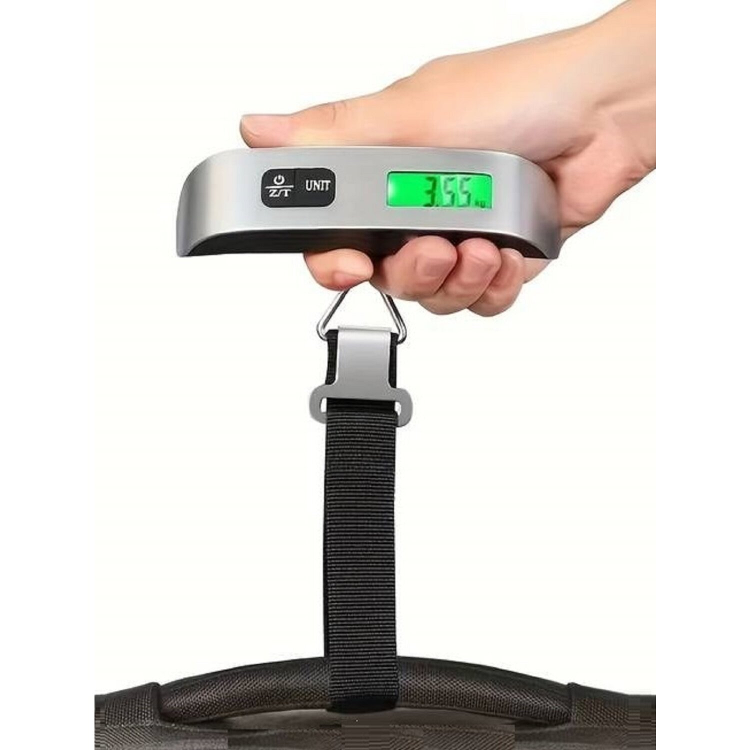 Eine Hand hält eine Gepäckwaage. Die Waage zeigt ein Gewicht von 3,55.