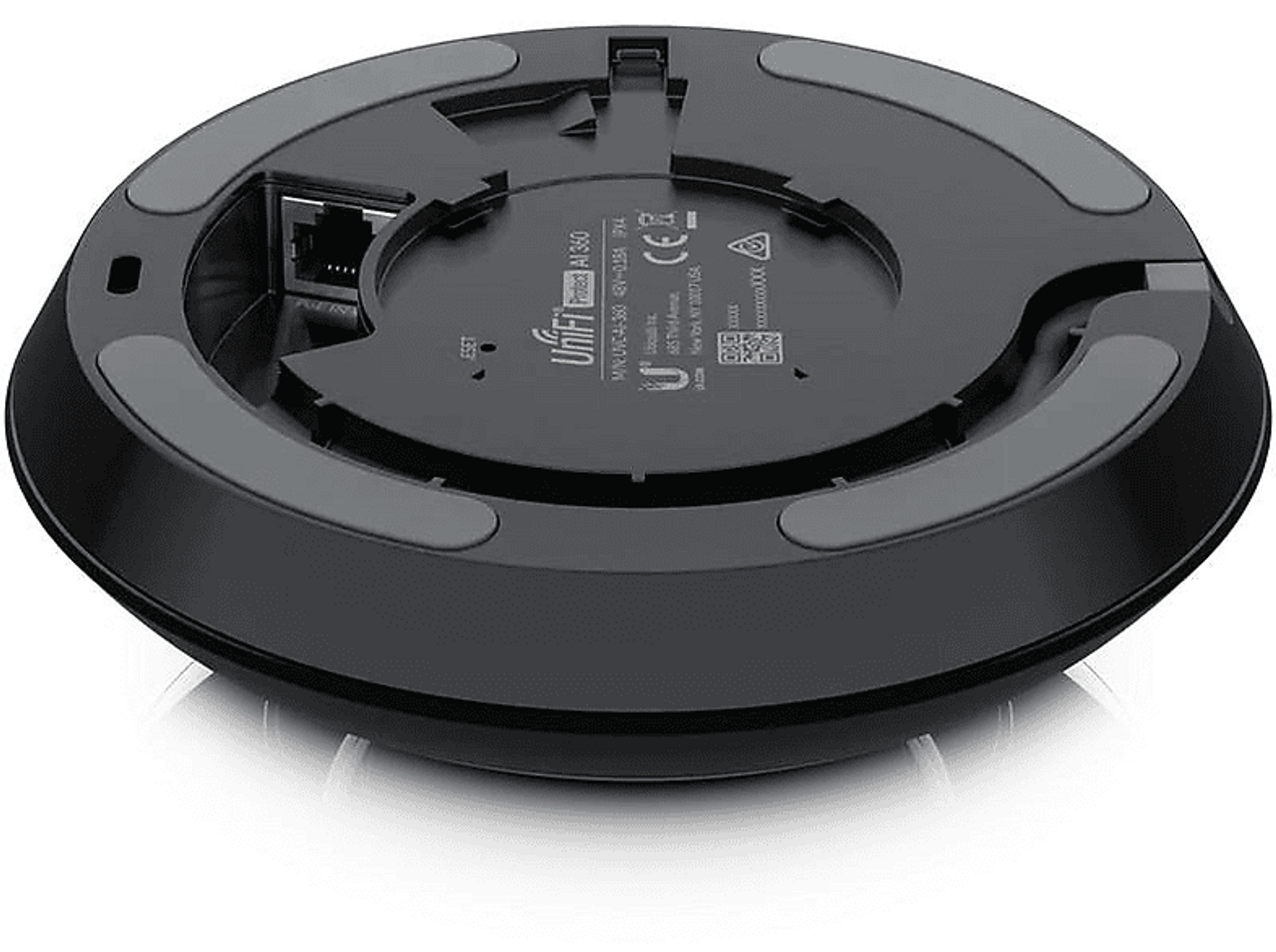 Czarne, okrągłe urządzenie sieciowe, widok od dołu, z widocznymi portami i etykietami.