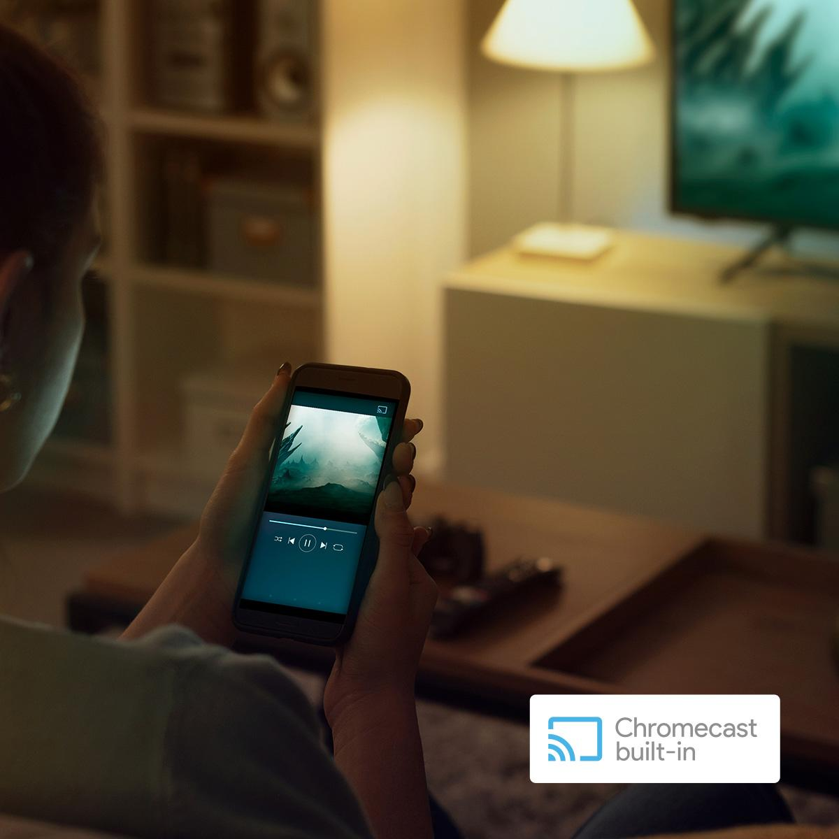 Kobieta trzymająca smartfon z filmem i logo Chromecast.