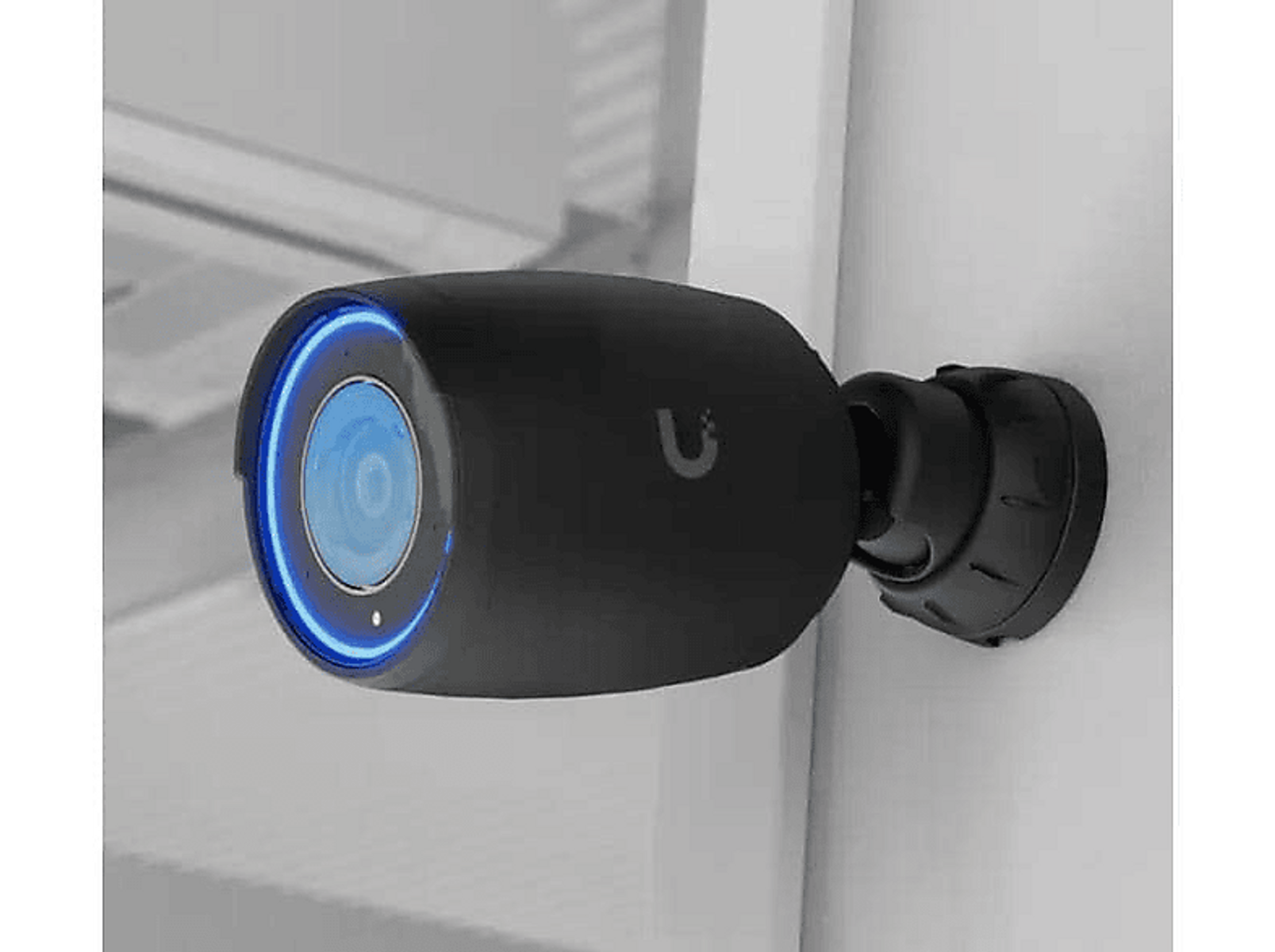 Czarna kamera bezpieczeństwa na białej ścianie, z niebieskim pierścieniem.