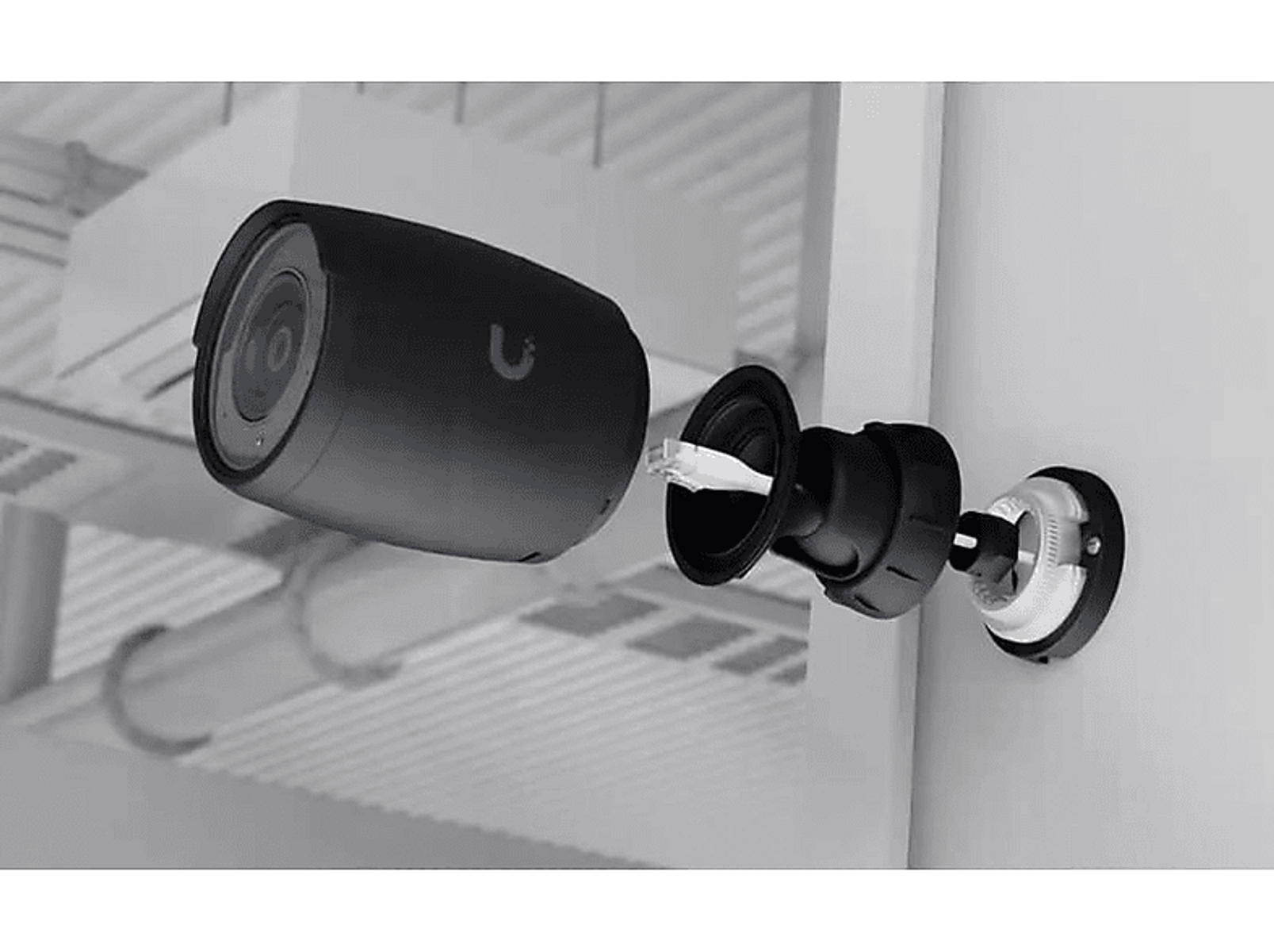 Widok rozstrzelony kamery bezpieczeństwa. Kamera jest czarna, z białą podstawą i połączeniem.