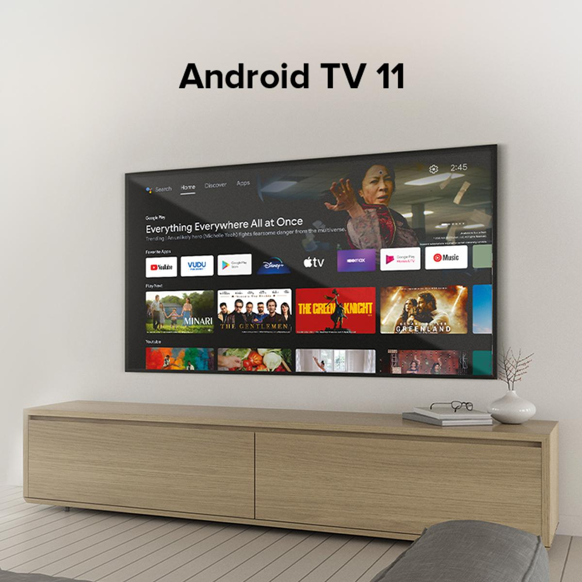 Telewizor z dużym ekranem, wyświetlający interfejs Android TV 11 na drewnianej szafce.