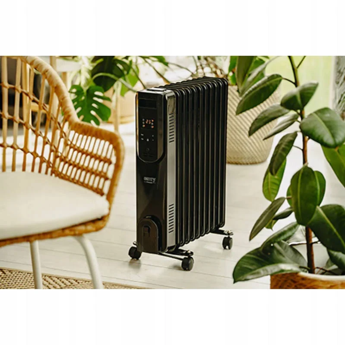 Czarny grzejnik olejowy na kółkach obok krzesła i roślin.