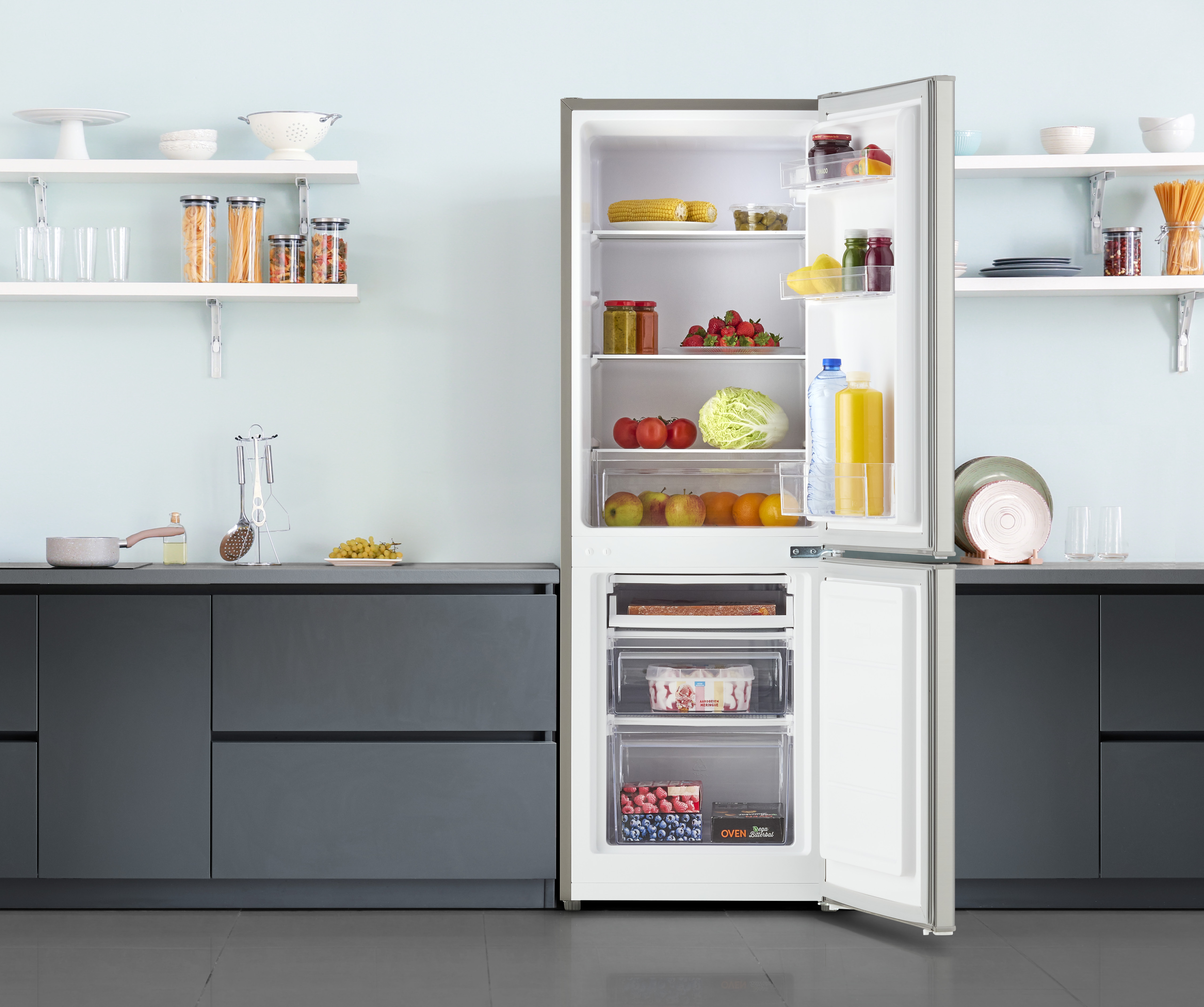 White refrigerator with the door open. Inside the refrigerator is food. Kitchen background.