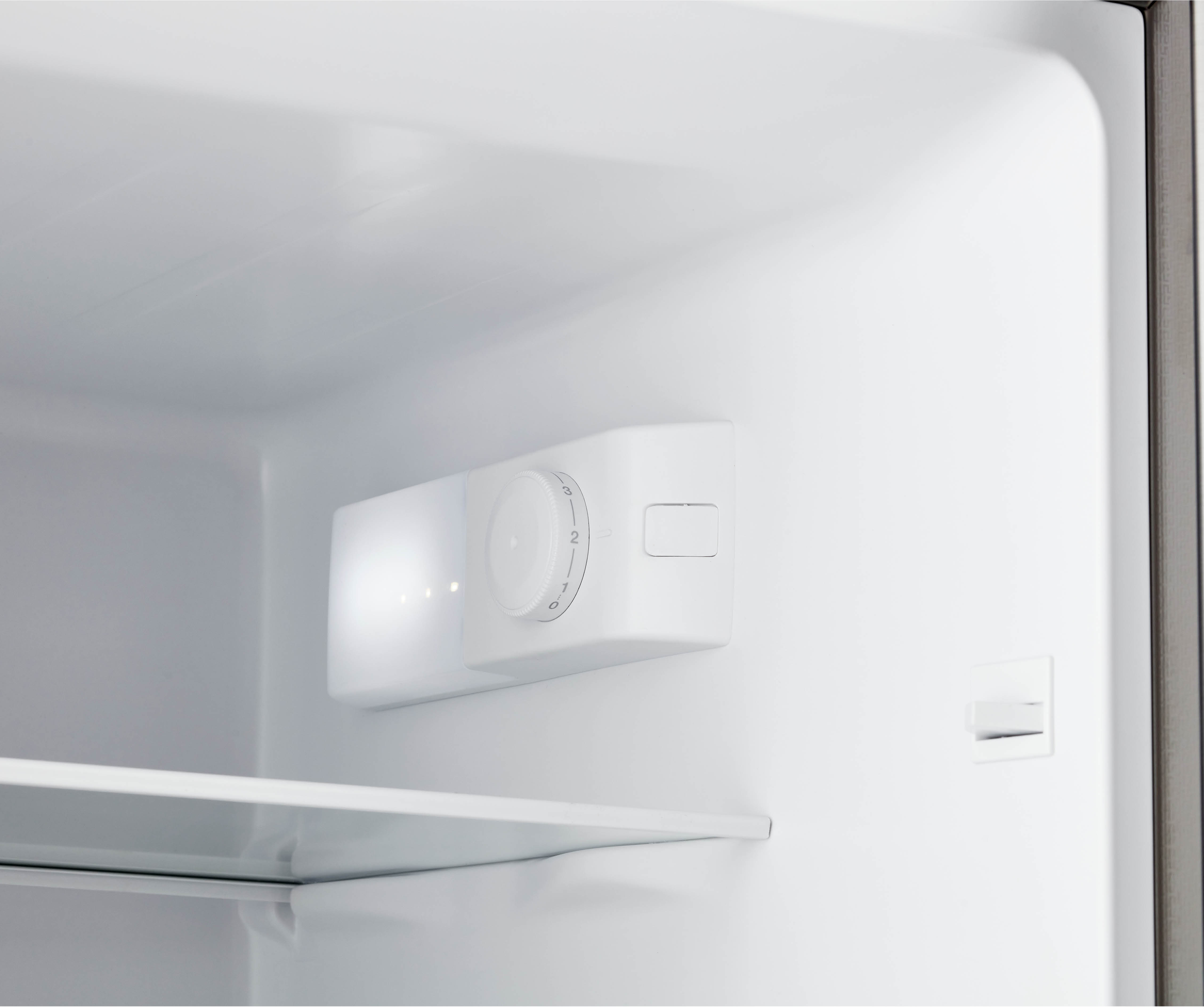 Inside a refrigerator with a white control panel and a shelf. White background.