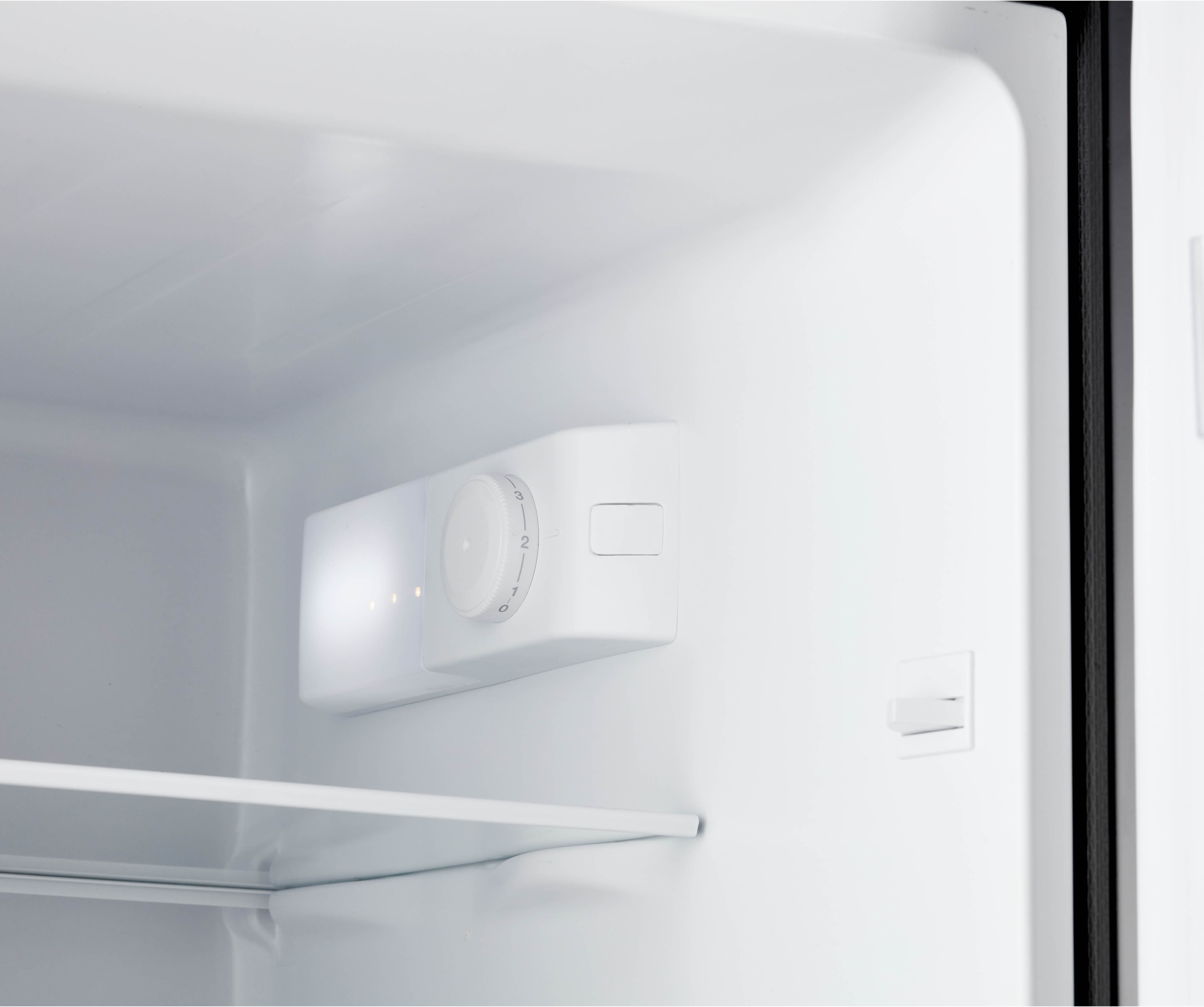 Inside a refrigerator with white shelves, a temperature control panel is visible.