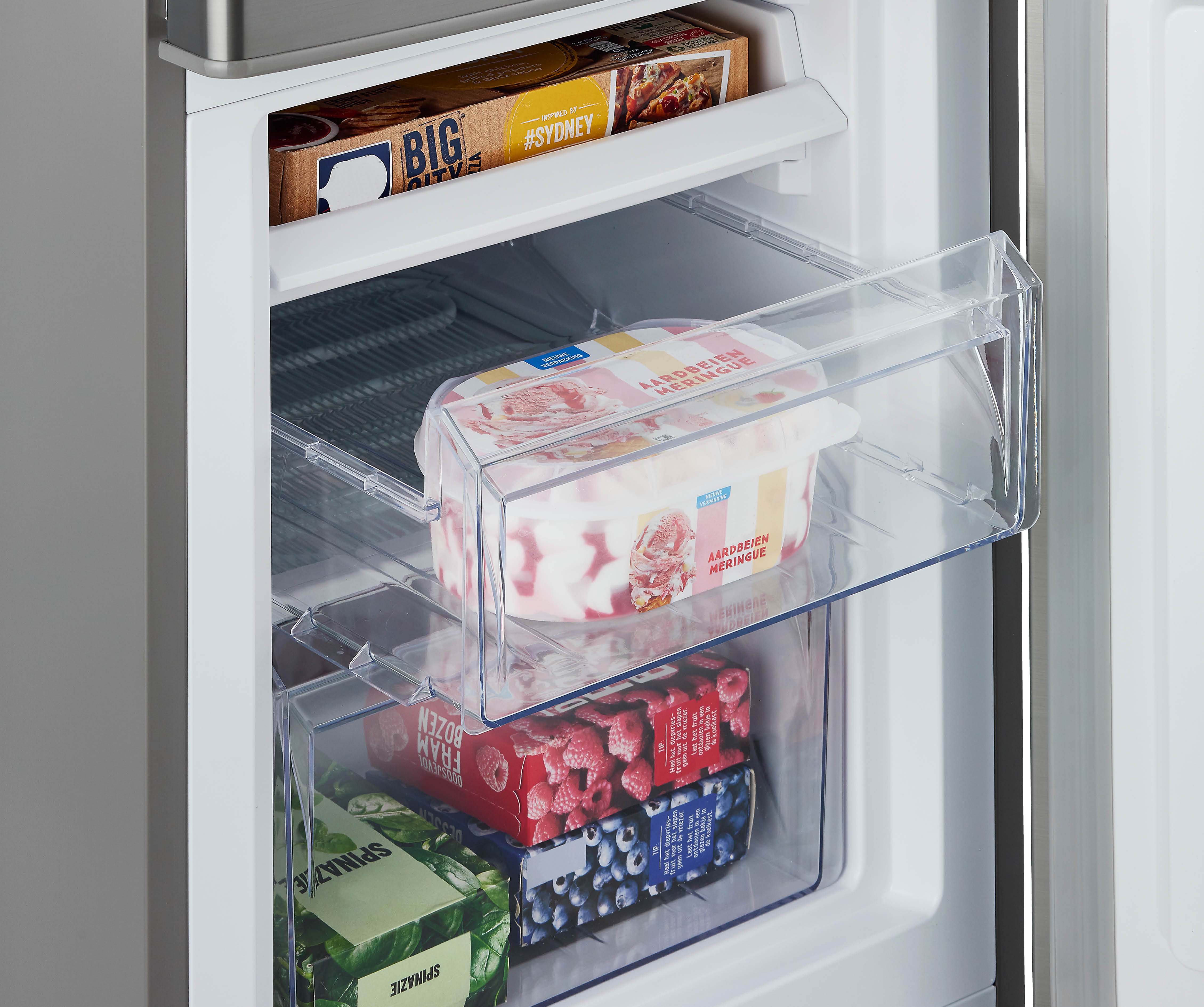 Inside a refrigerator with drawers. There are frozen goods like ice cream and frozen berries.