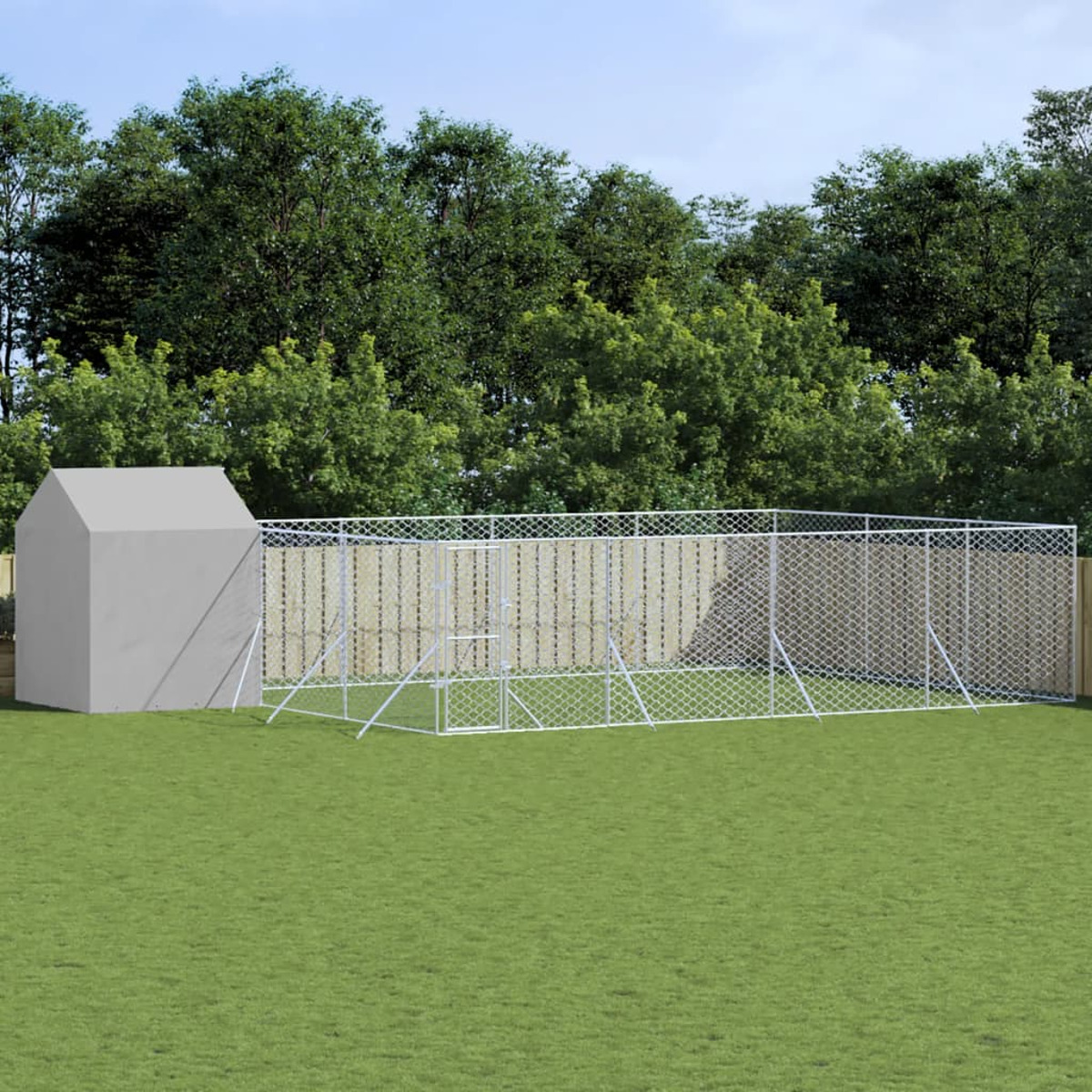 Ein Hundeauslauf aus Maschendrahtzaun und ein kleiner Unterstand auf einer grünen Wiese.