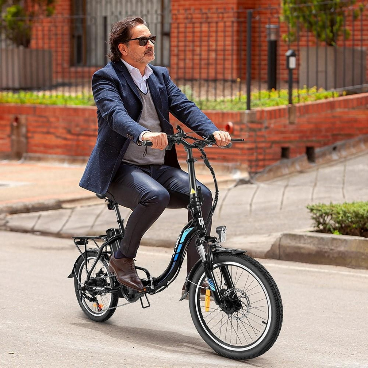 Uomo in giacca e cravatta in sella a una bicicletta elettrica nera in una strada cittadina, giornata di sole.
