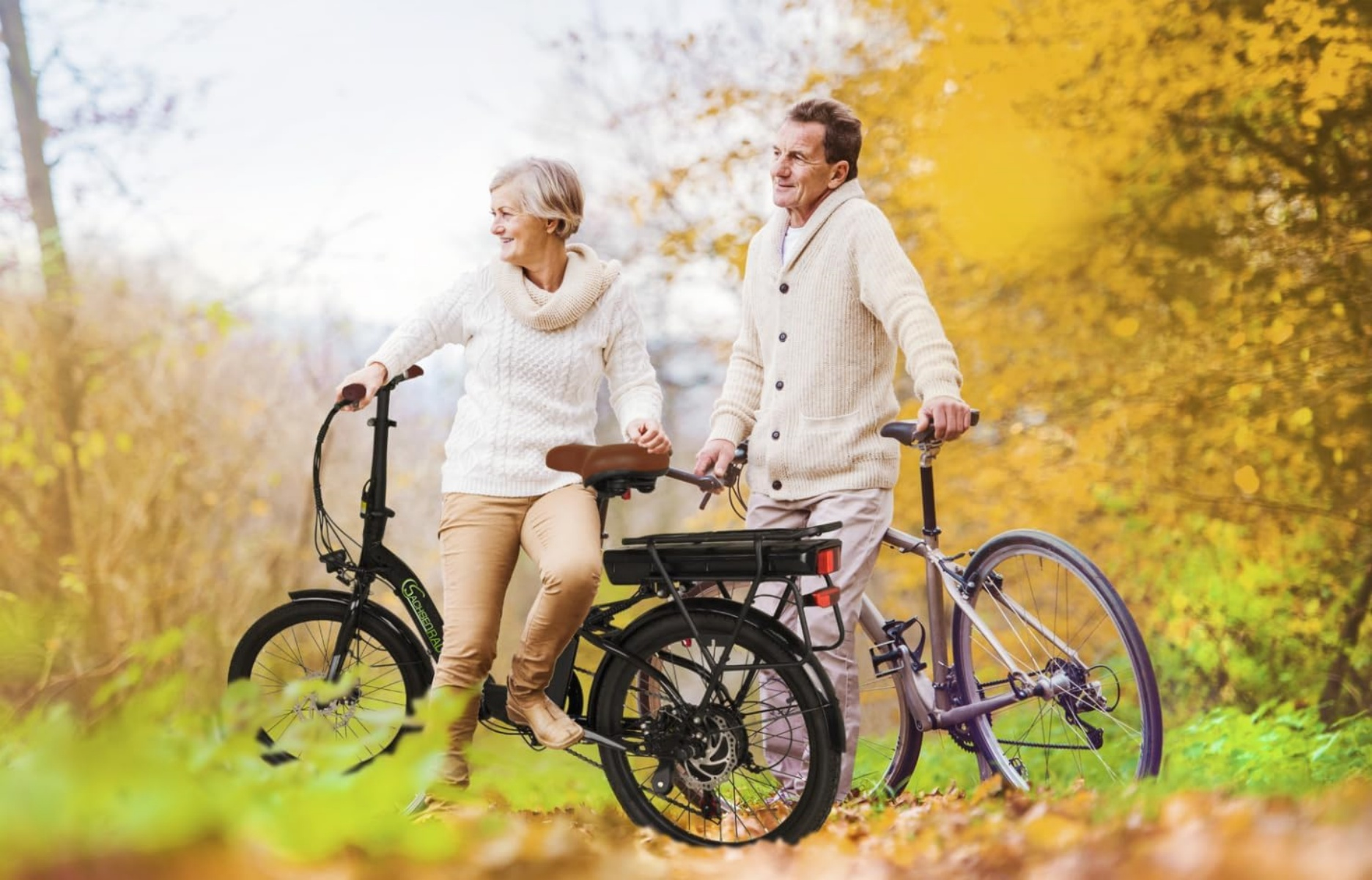 Ein älteres Ehepaar steht mit Fahrrädern inmitten von Herbstlaub.