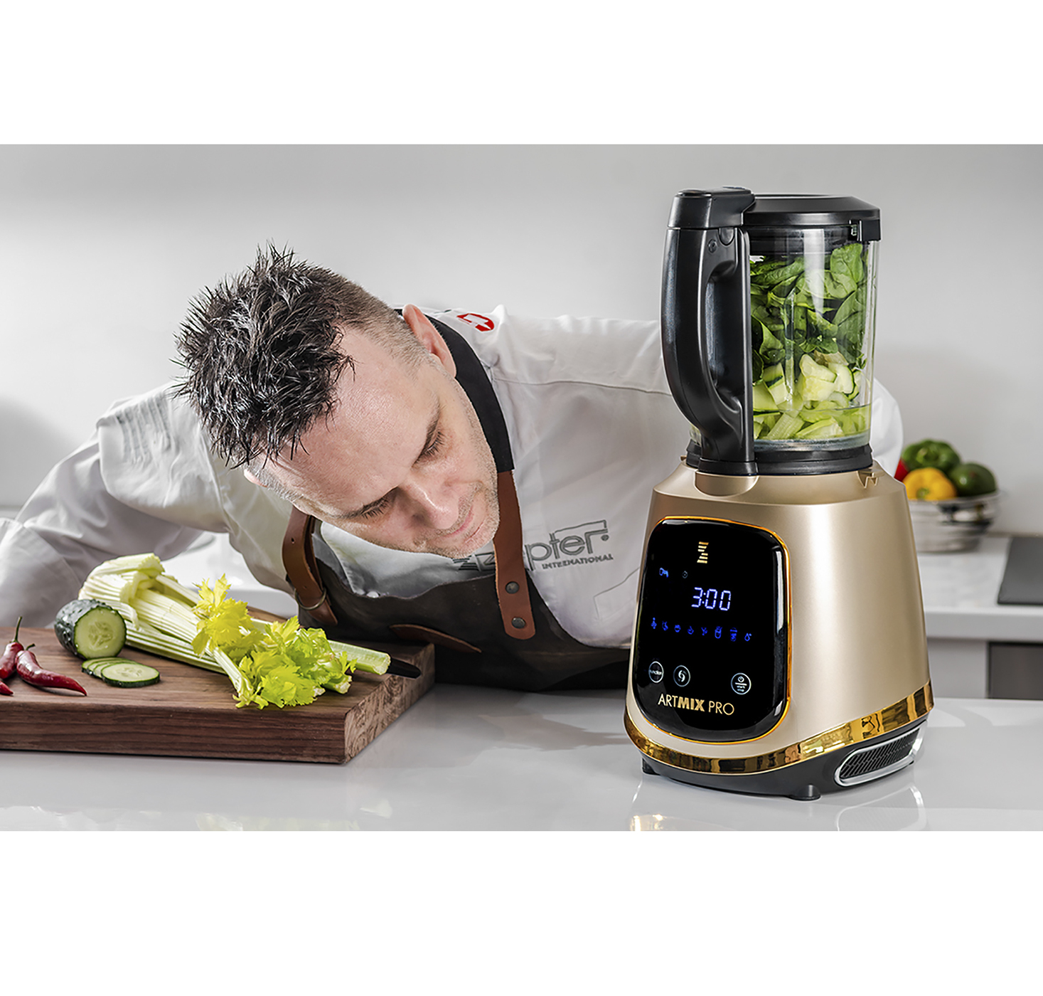 Ein Koch bereitet Zutaten neben einem goldenen Mixer zu, mit Gemüse und einem Schneidebrett.