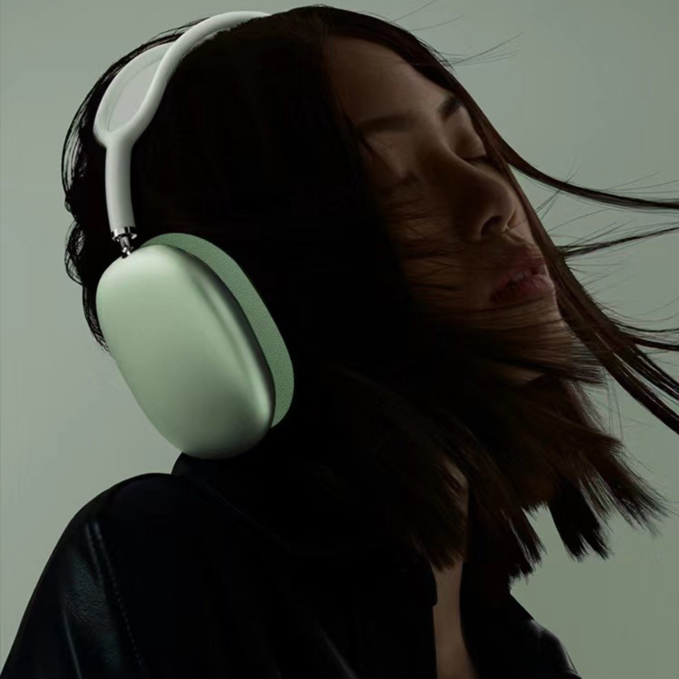 Kobieta w zielonych słuchawkach, zamknięte oczy, włosy na wietrze.