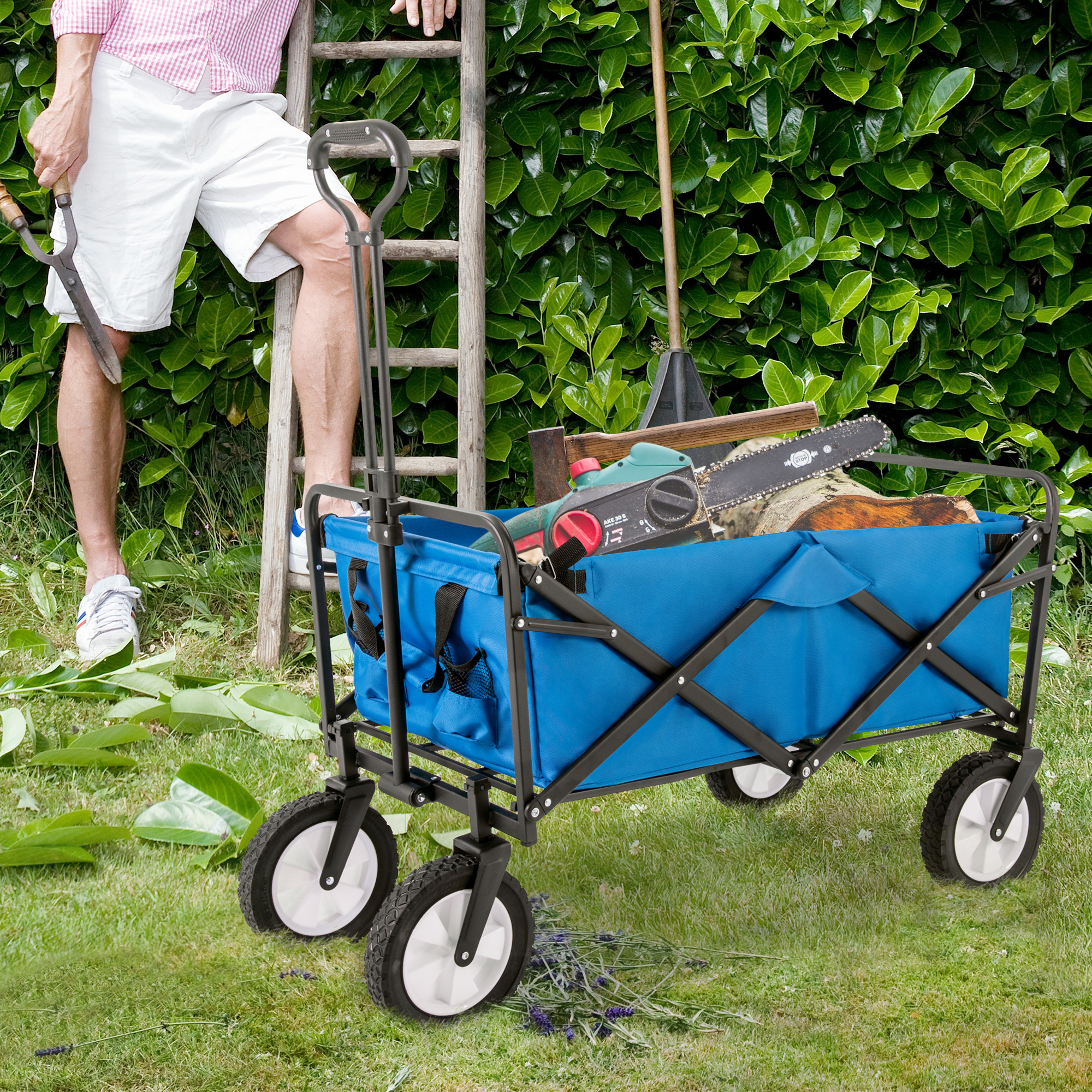 Blauer Gartenwagen mit Werkzeug und Person, Leiter und Grün im Hintergrund.