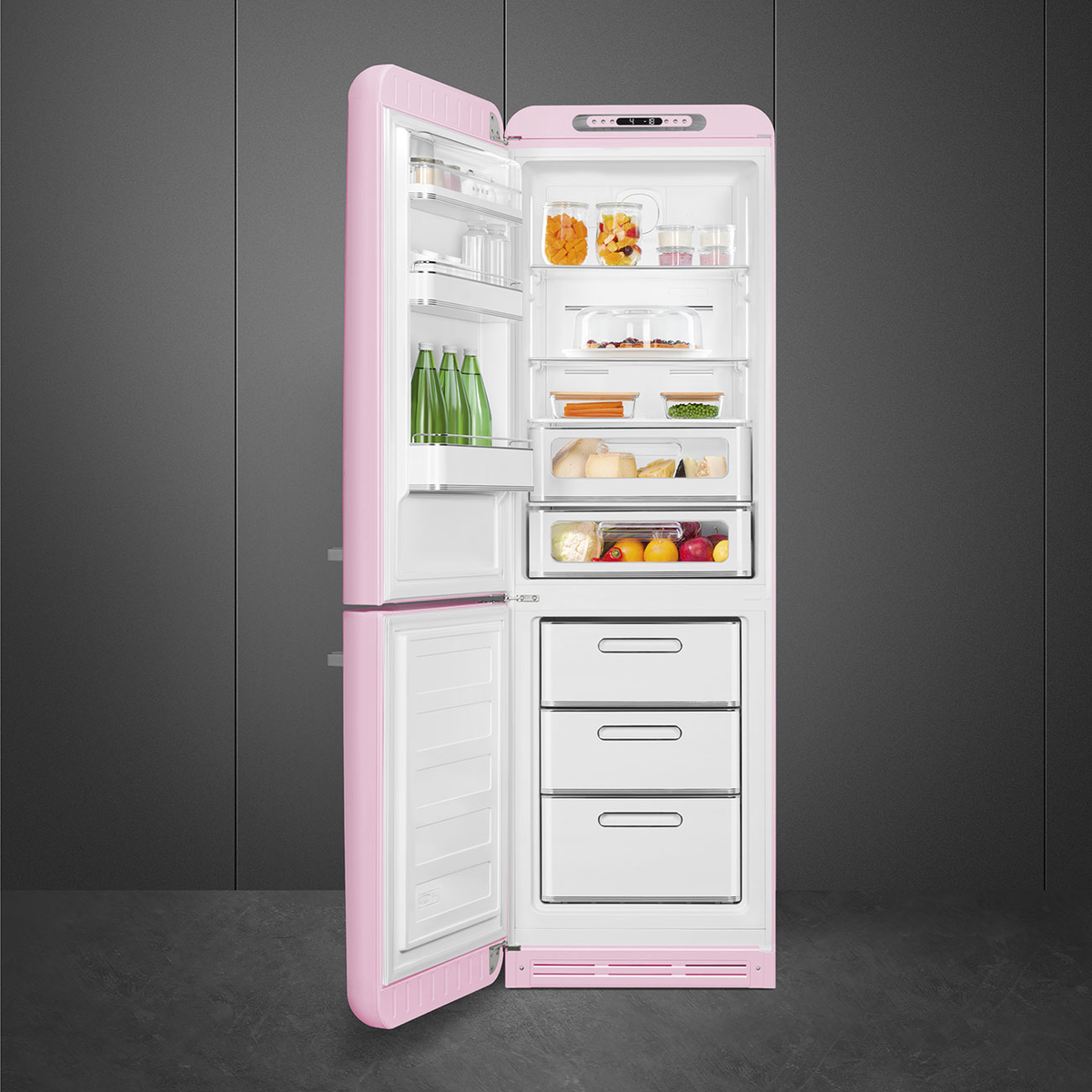 Refrigerador Smeg rosa, abierto, mostrando alimentos en estantes, sobre fondo gris oscuro.