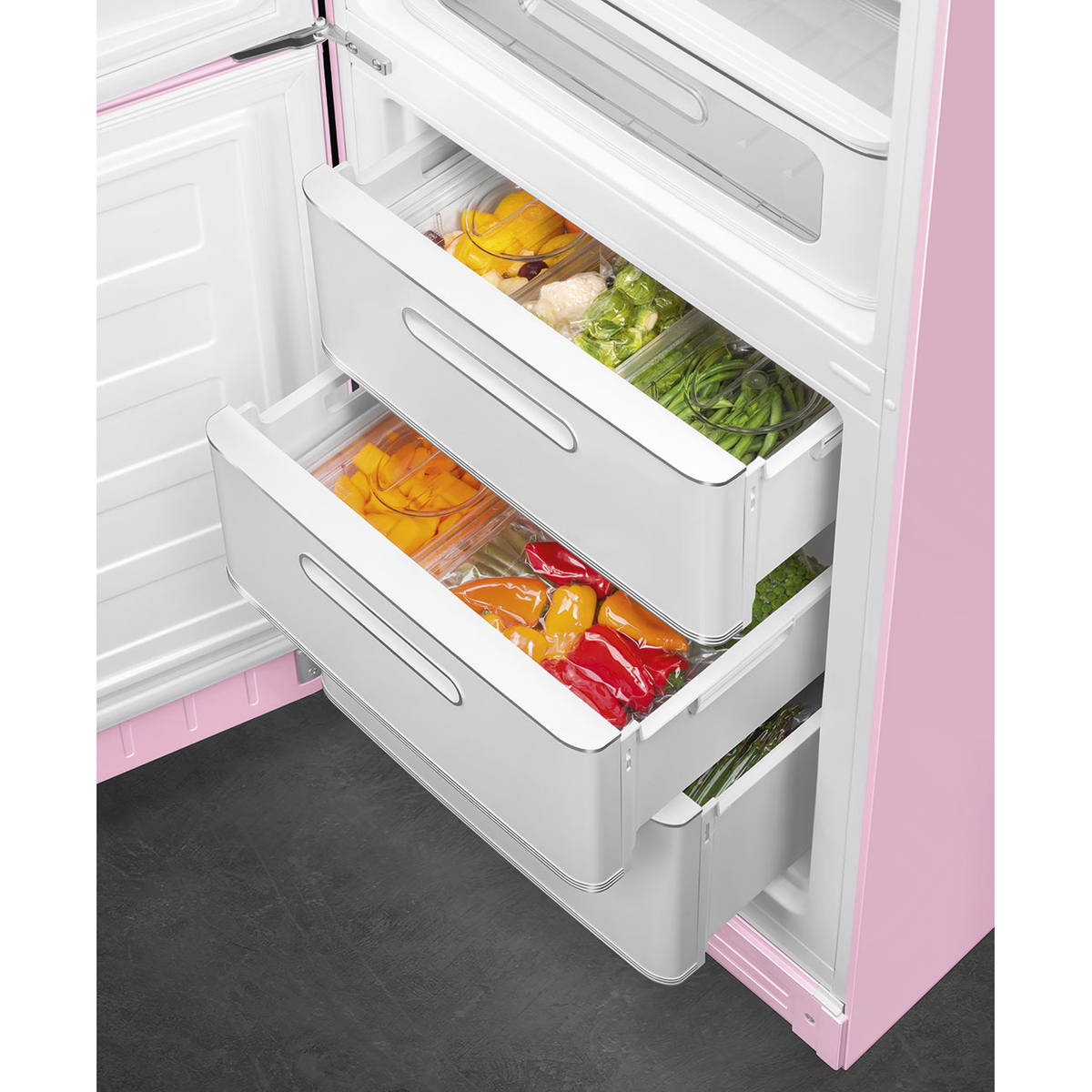 Cajones de nevera con verduras frescas en recipientes. Interior de nevera rosa.