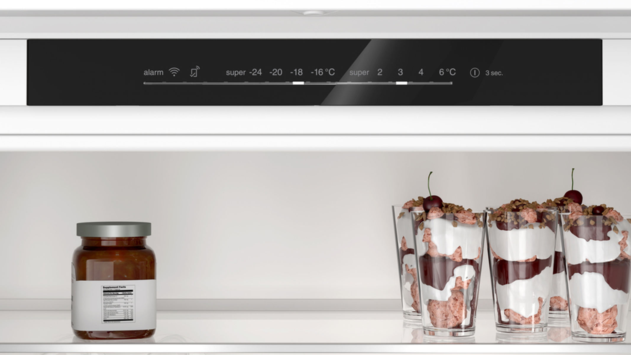 Wnętrze lodówki ze słoikami, deserami w szklankach i panelem sterowania na górze.