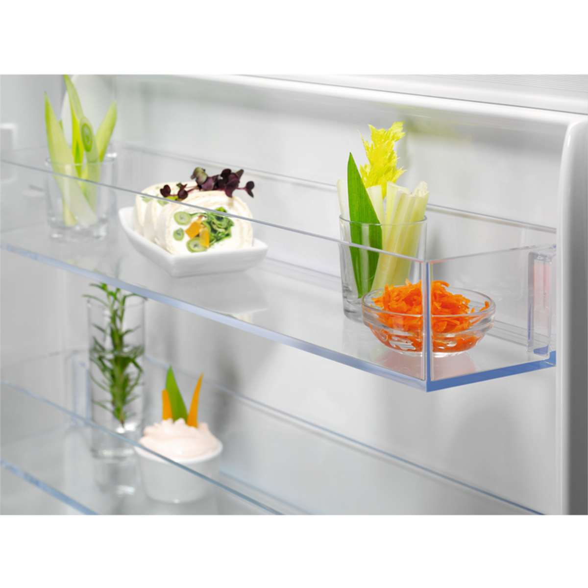 Wnętrze lodówki z warzywami w szklanych pojemnikach.