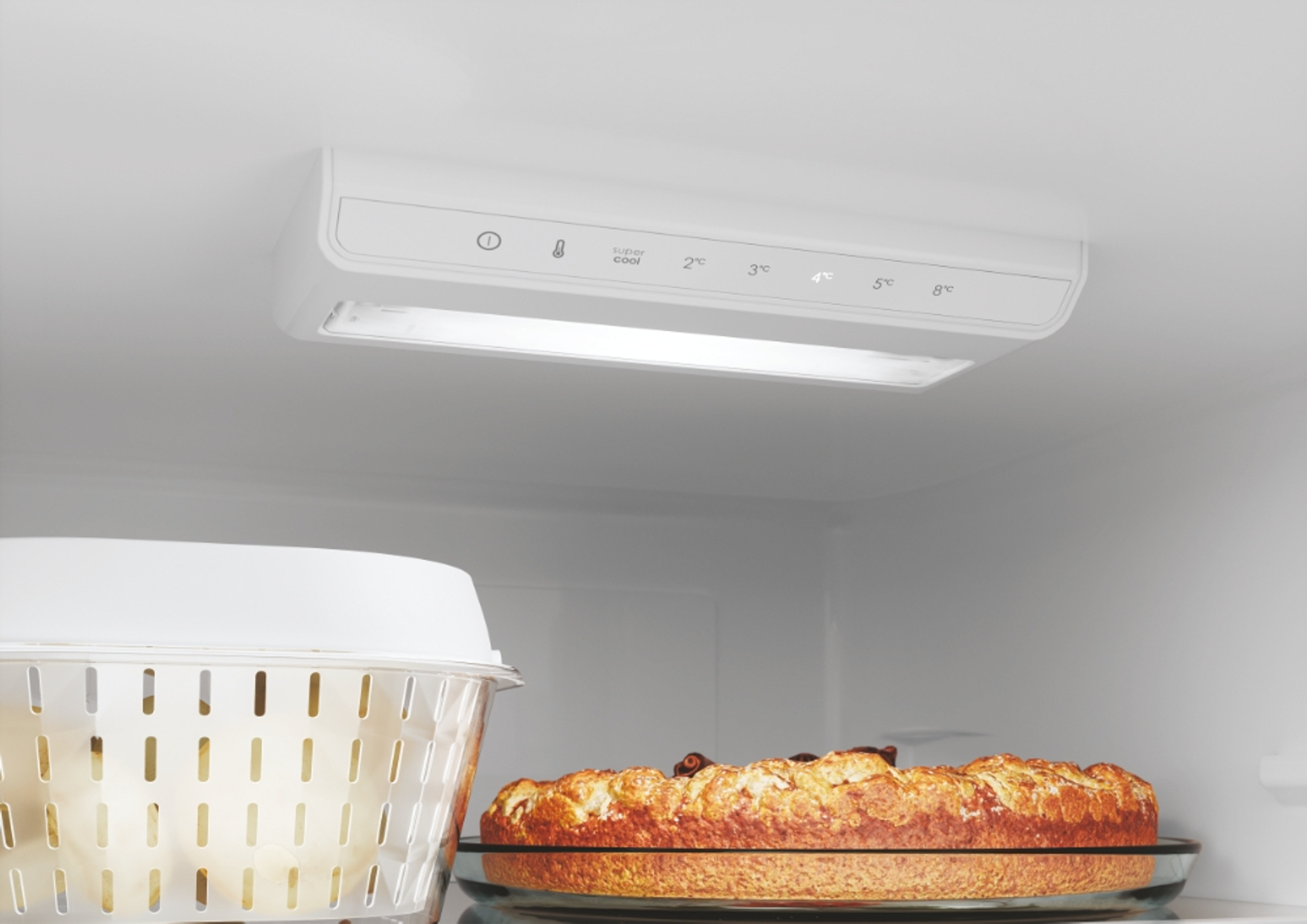 All'interno di un frigorifero, una torta su un piatto di vetro, vicino alla luce e ai comandi.