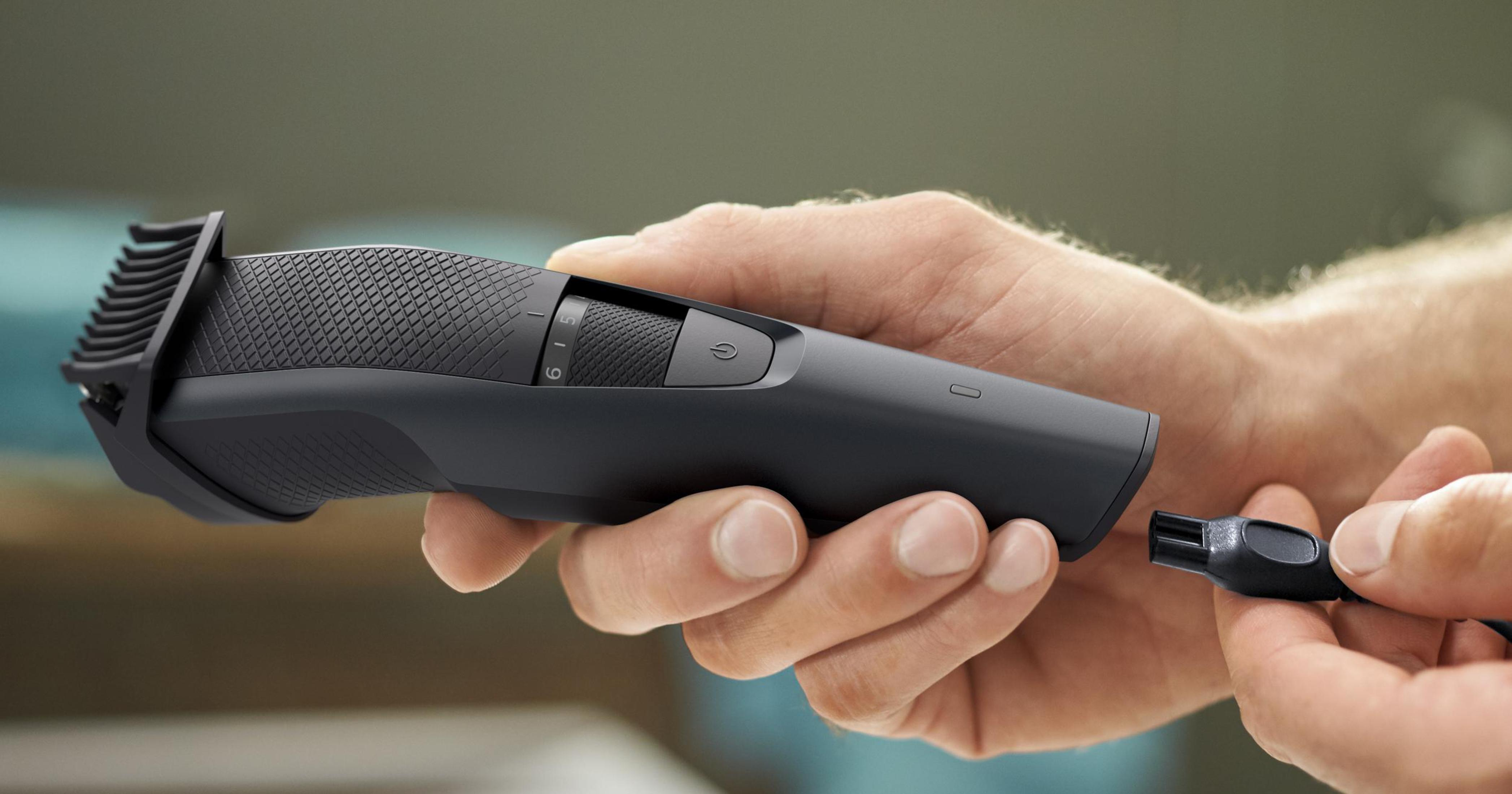 Ręka osoby trzyma czarną golarkę elektryczną i szczoteczkę do czyszczenia.