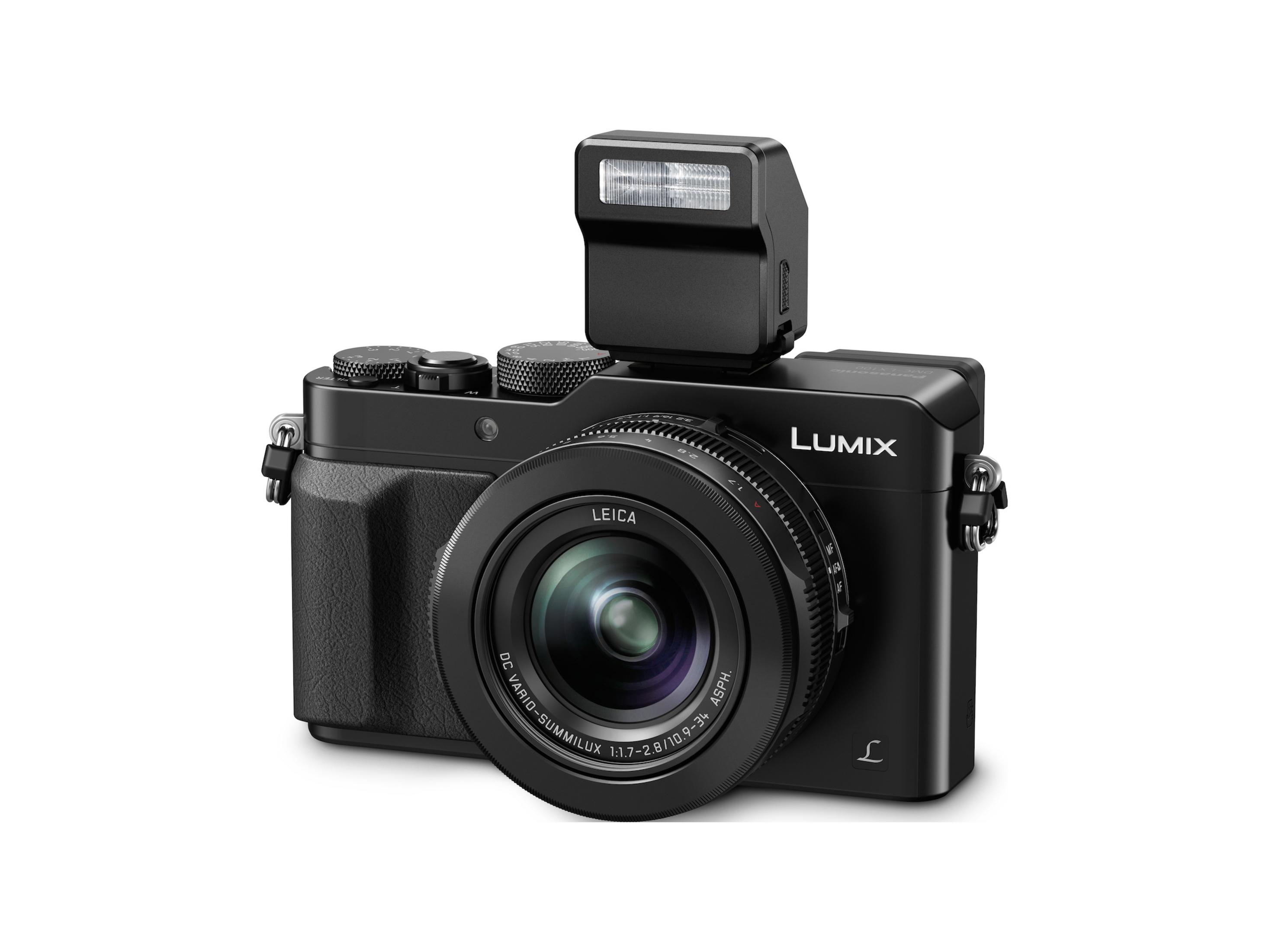Eine schwarze Leica-Kamera mit Blitz, Objektiv in der Mitte, vor weißem Hintergrund.