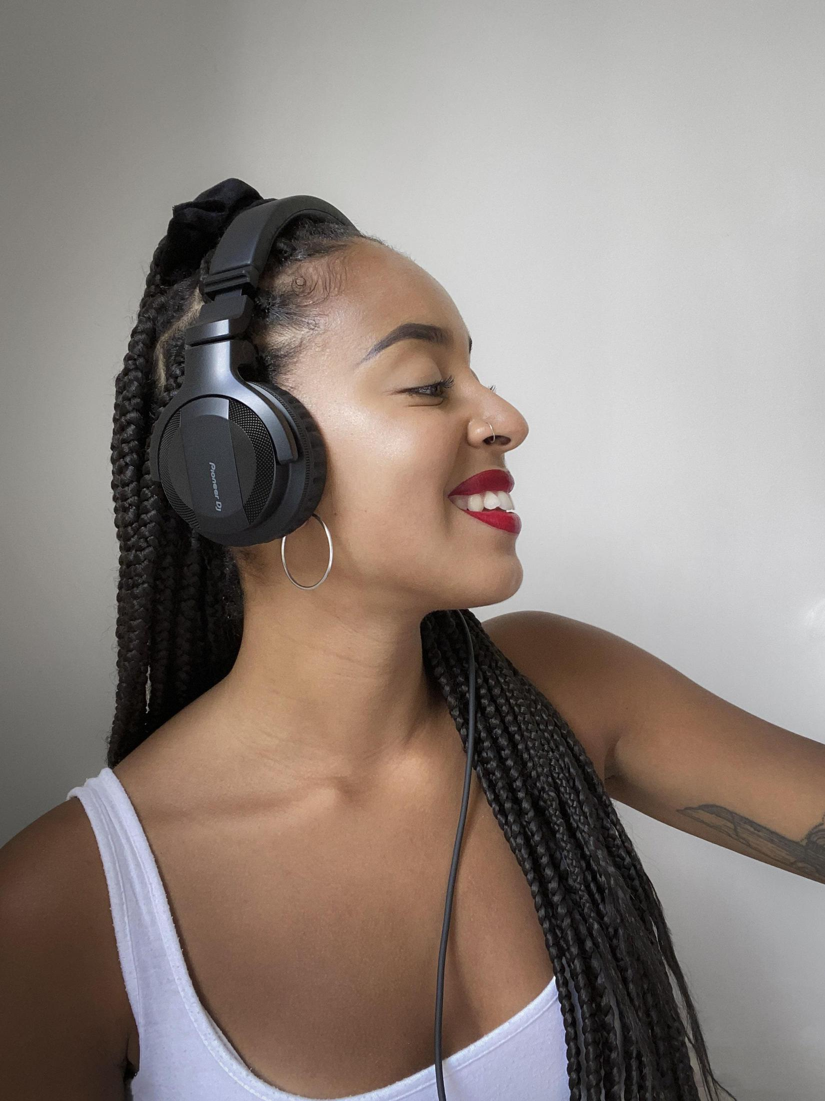 Kobieta z ciemnymi włosami w słuchawkach i uśmiechnięta. Widoczna czerwona szminka.