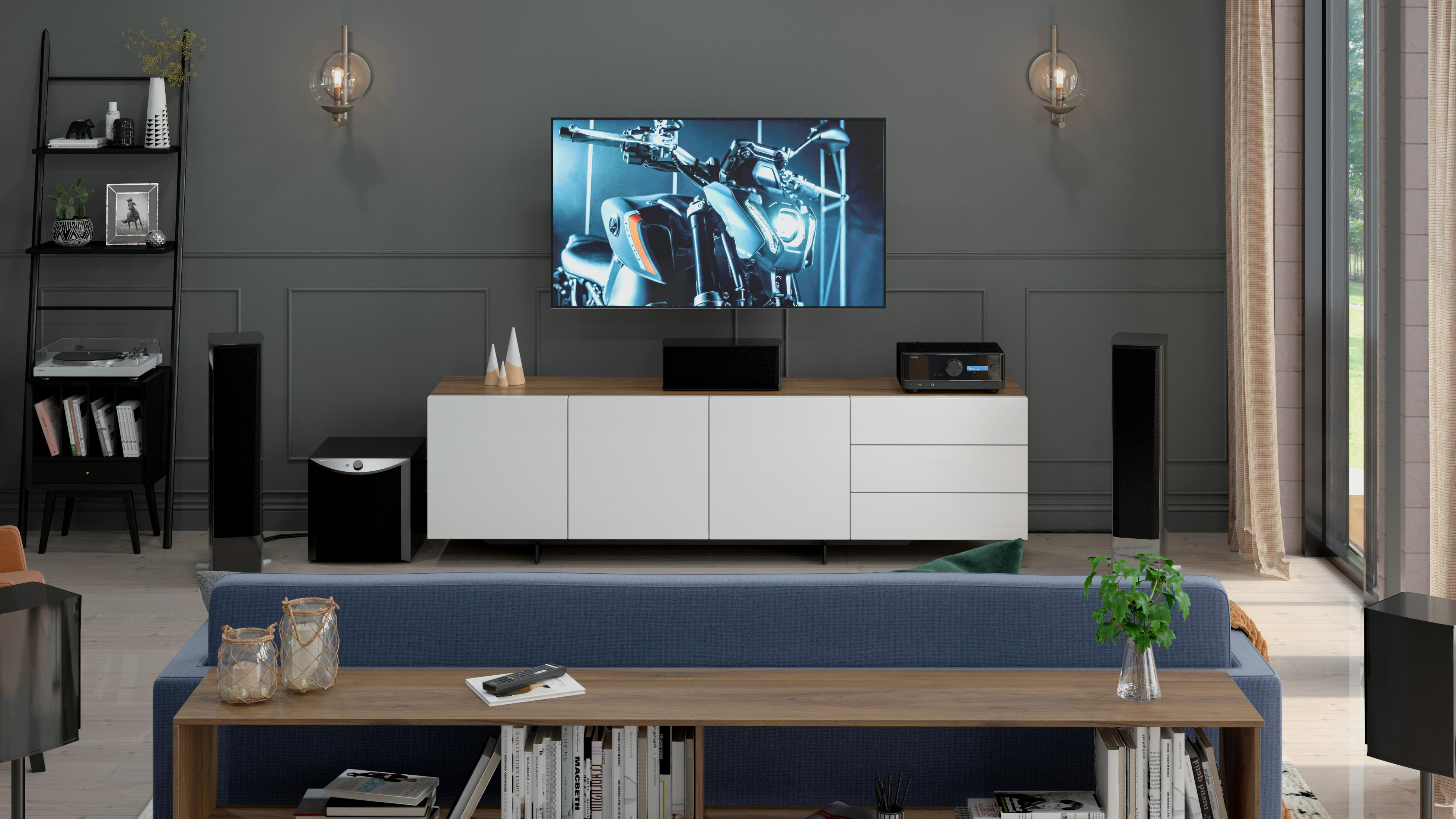 Ein Wohnzimmer mit Fernseher, Soundsystem, Sofa und Couchtisch mit Büchern und Dekorationen.
