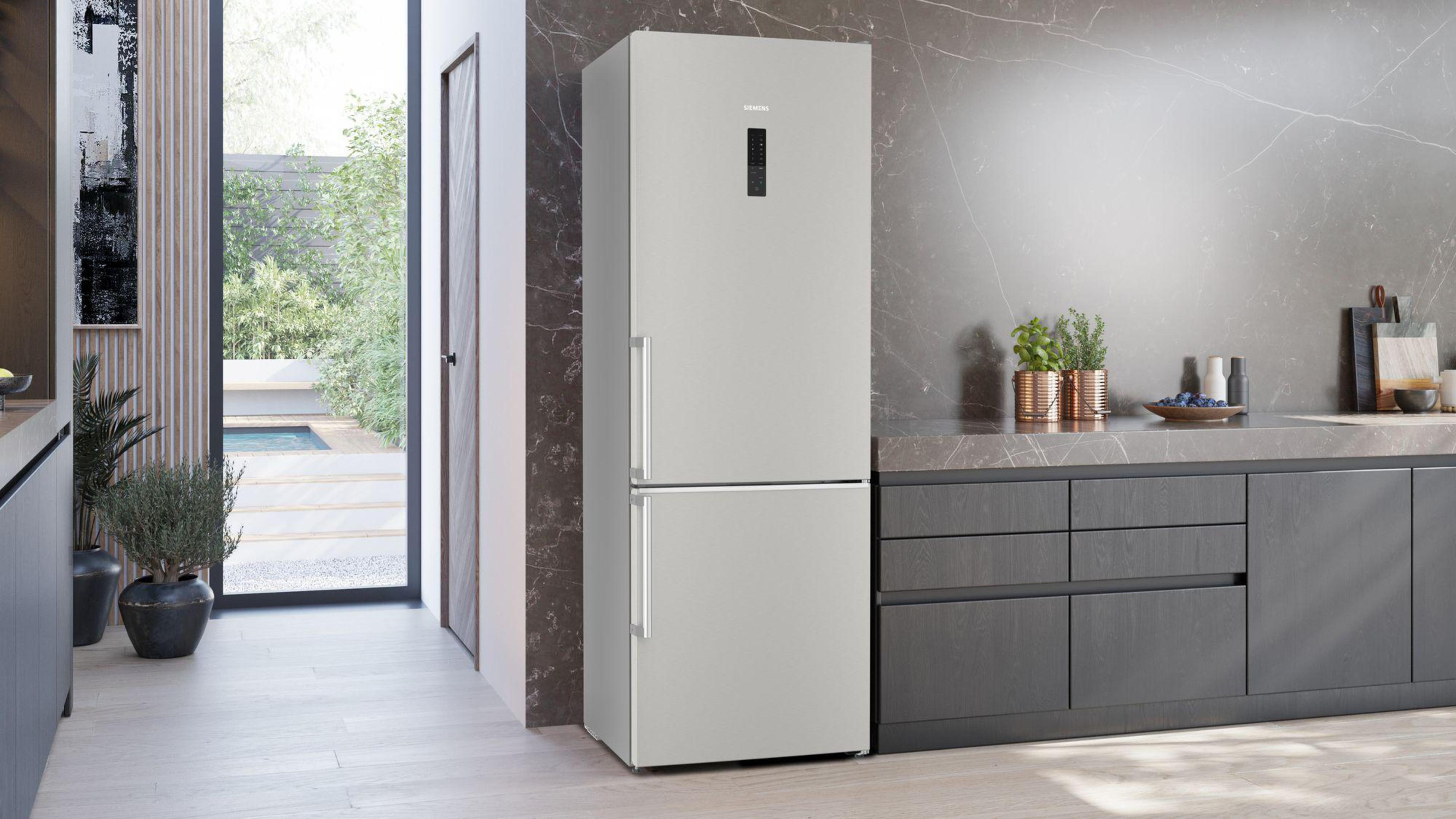 Silberner Siemens-Kühlschrank in moderner Küche. Dunkelgraue Schränke, marmorartige Wand, Pflanzen.
