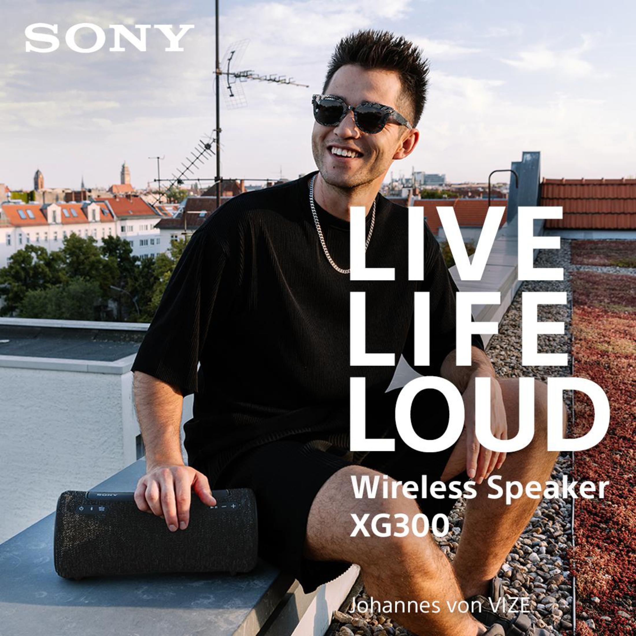 Ein Mann mit Sonnenbrille hält einen schwarzen Lautsprecher und Text 'Live Life Loud'.