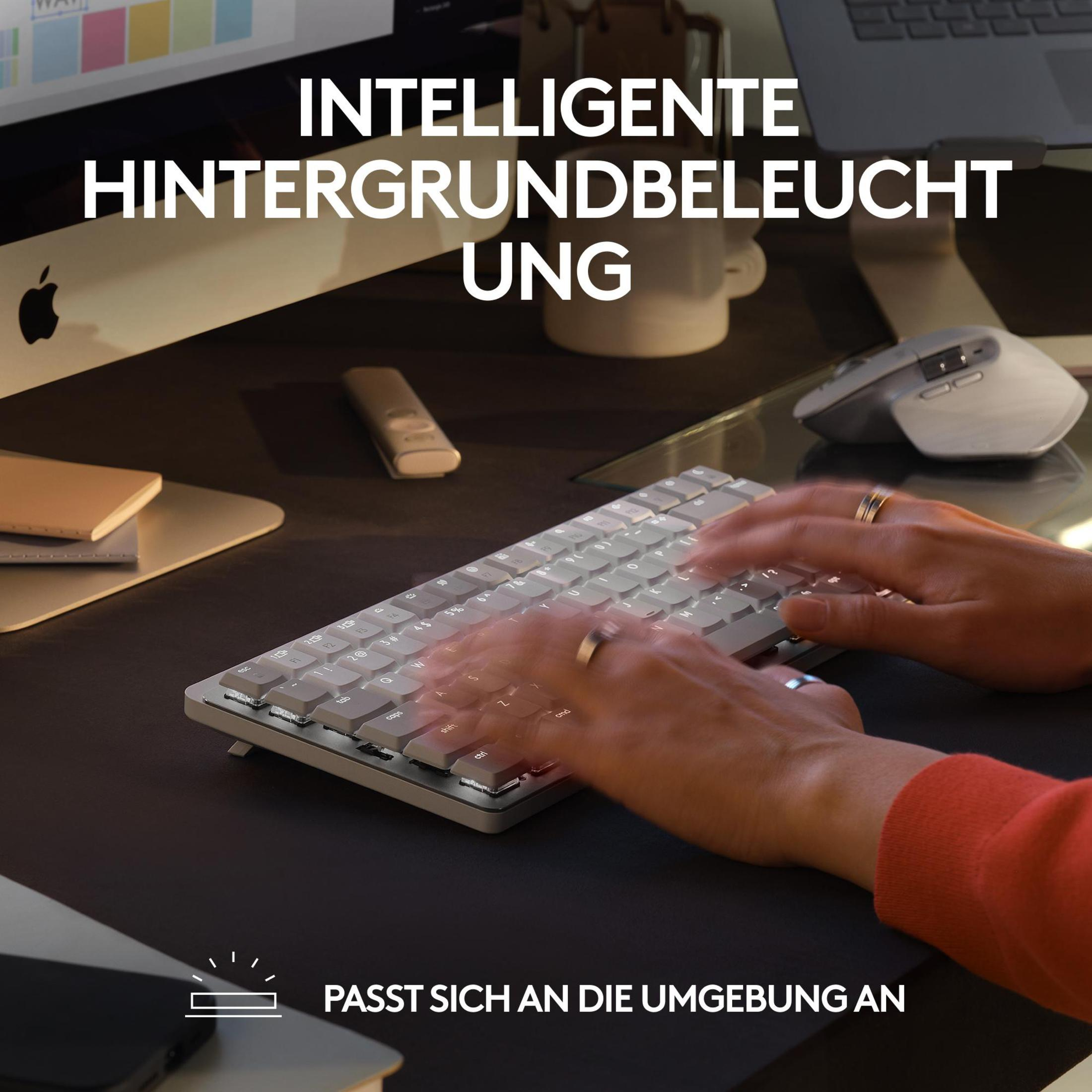 Mani che digitano su una tastiera retroilluminata con luci e un mouse bianco su una scrivania.