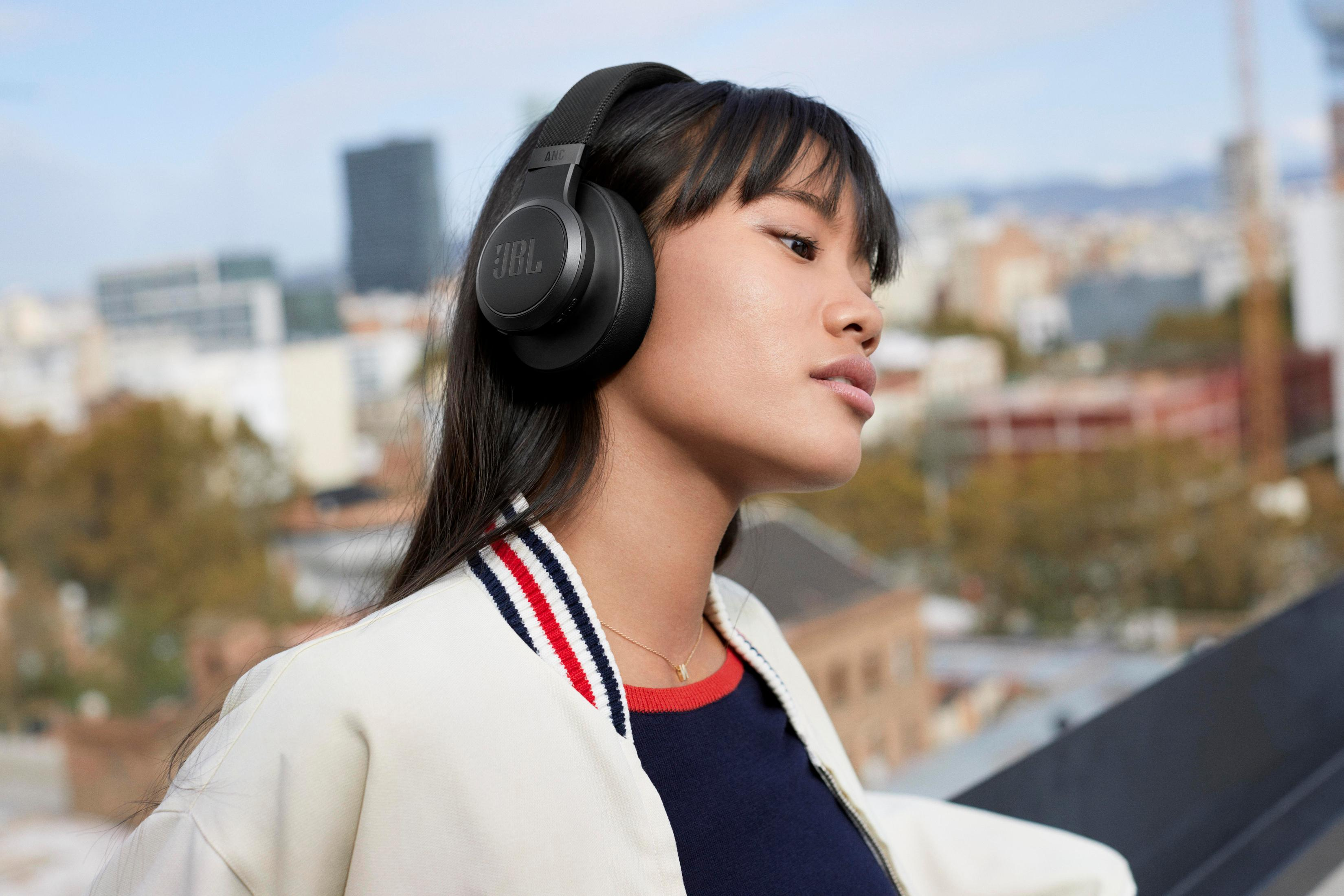 Kobieta w czarnych słuchawkach JBL na dachu.