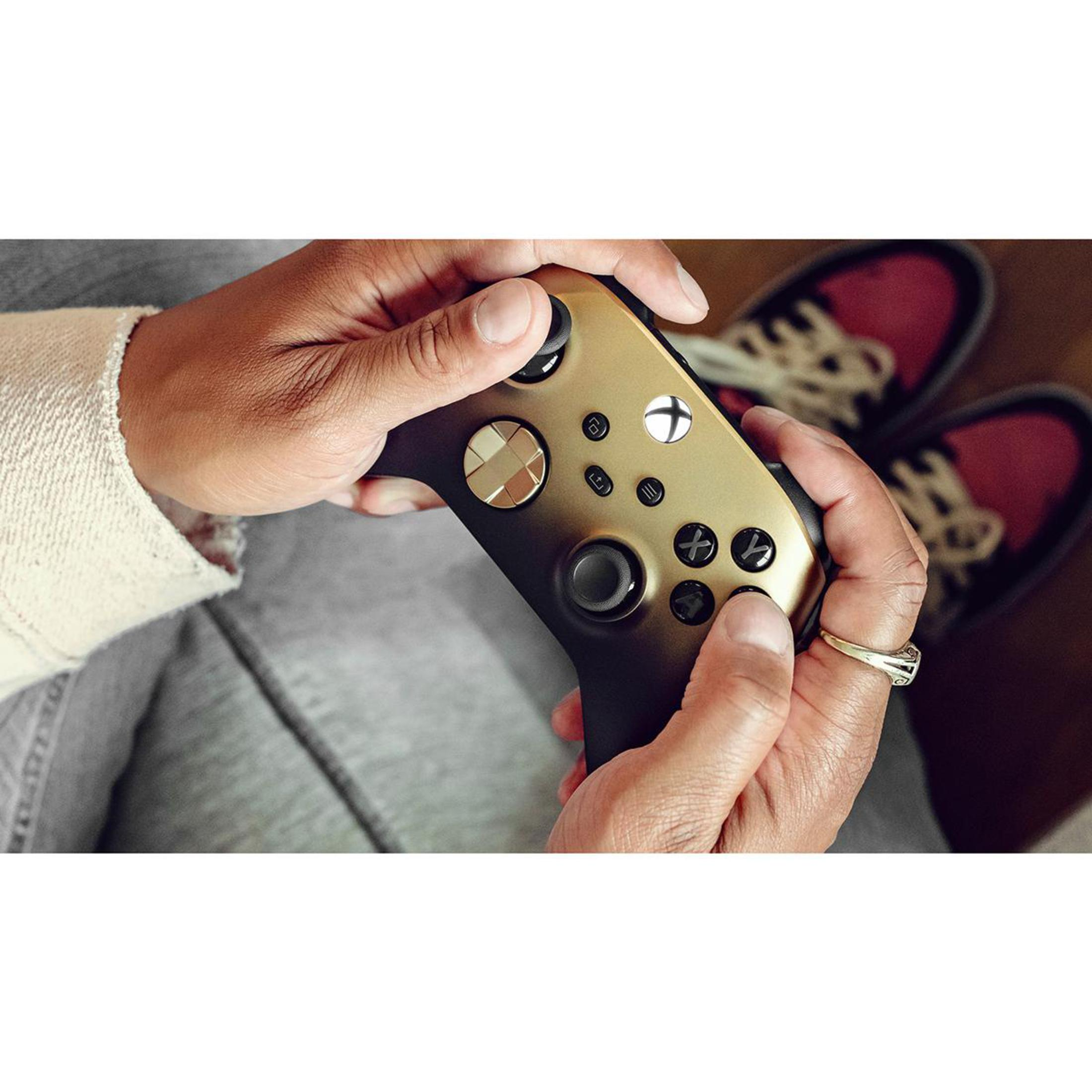 Hände halten einen gold-schwarzen Xbox-Controller, mit einem Ring an einem Finger.
