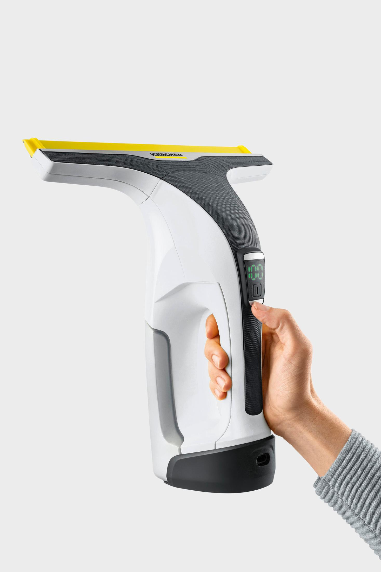 Dłoń osoby trzymającej biało-szarą myjkę do okien z żółtym ostrzem.