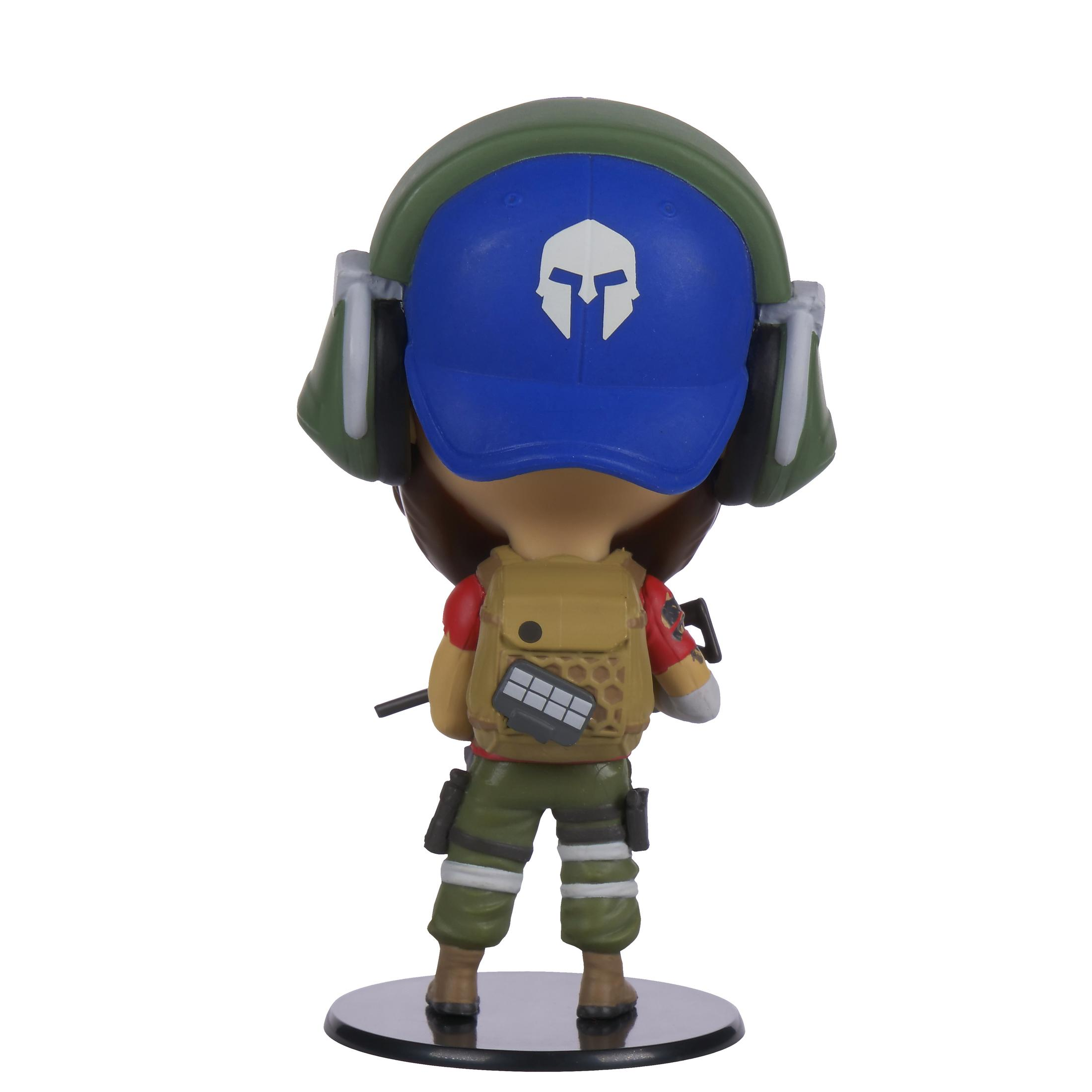 Eine Spielzeugfigur einer Figur mit blauer Kappe, grünen Ohrenschützern und einem beigefarbenen Rucksack.