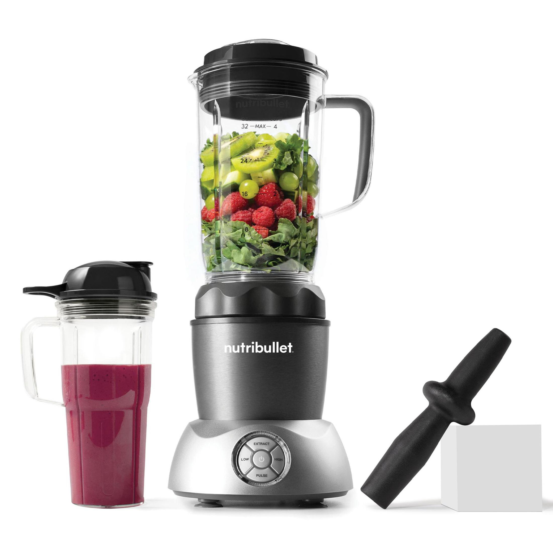 Un frullatore con ingredienti all'interno, un bicchiere per frullati e un pestello, tutto su una superficie bianca.