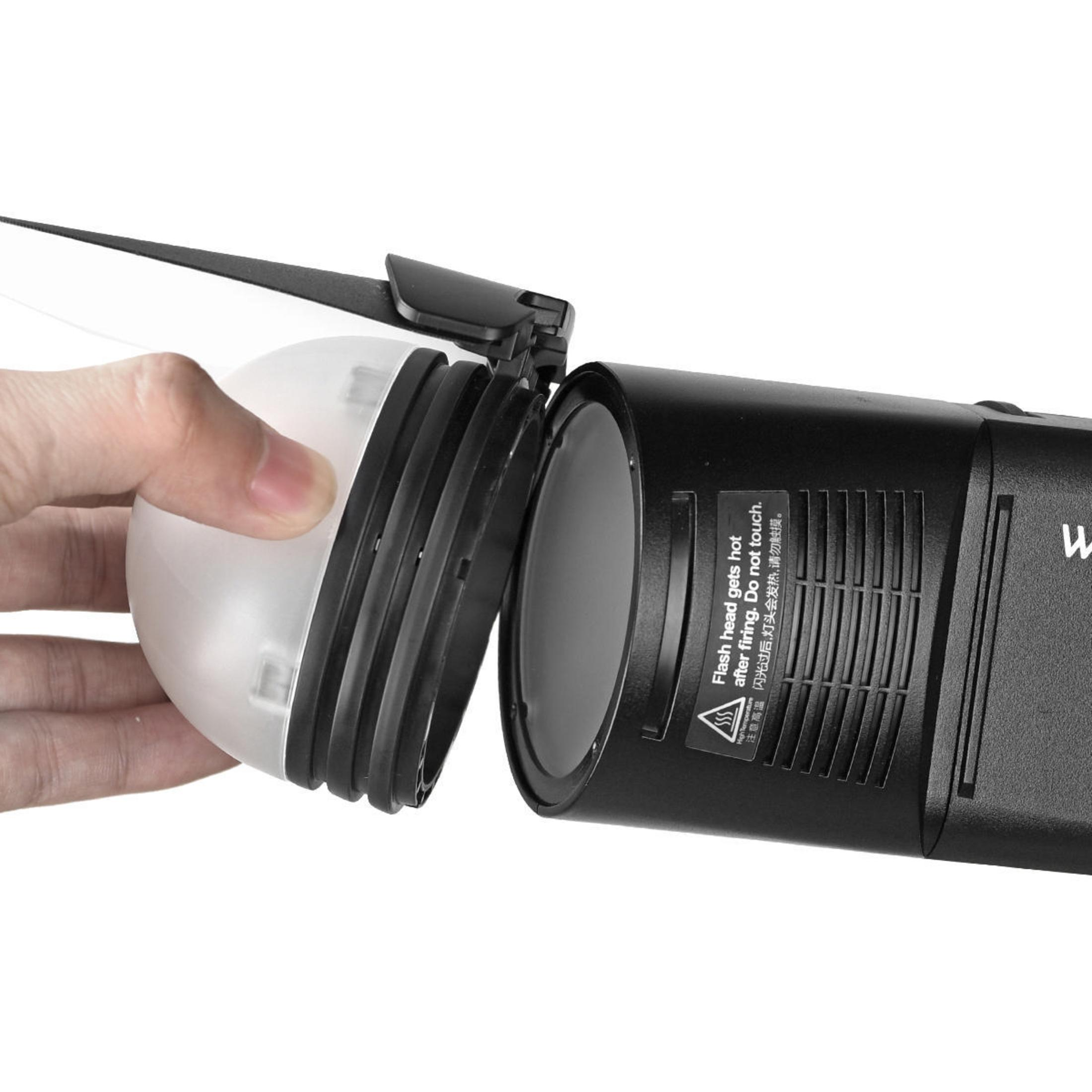 Hand öffnet einen Blitzdiffusor. Der Blitz ist schwarz, der Diffusor ist weiß.